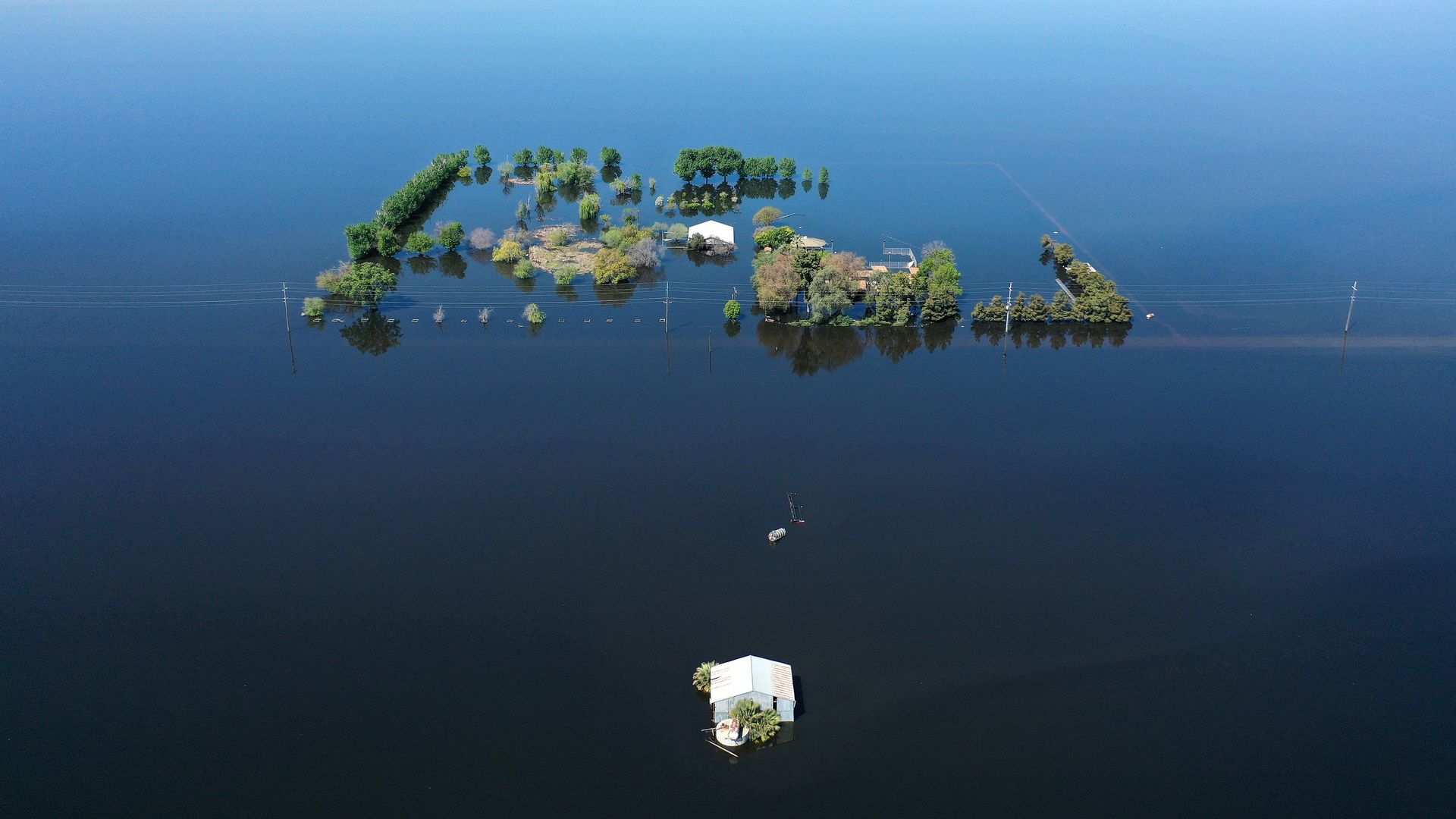 An aerial view of a home (C) surrounded by floodwaters in the reemerging Tulare Lake, in California’s Central Valley, on April 14, 2023 in Corcoran, California.