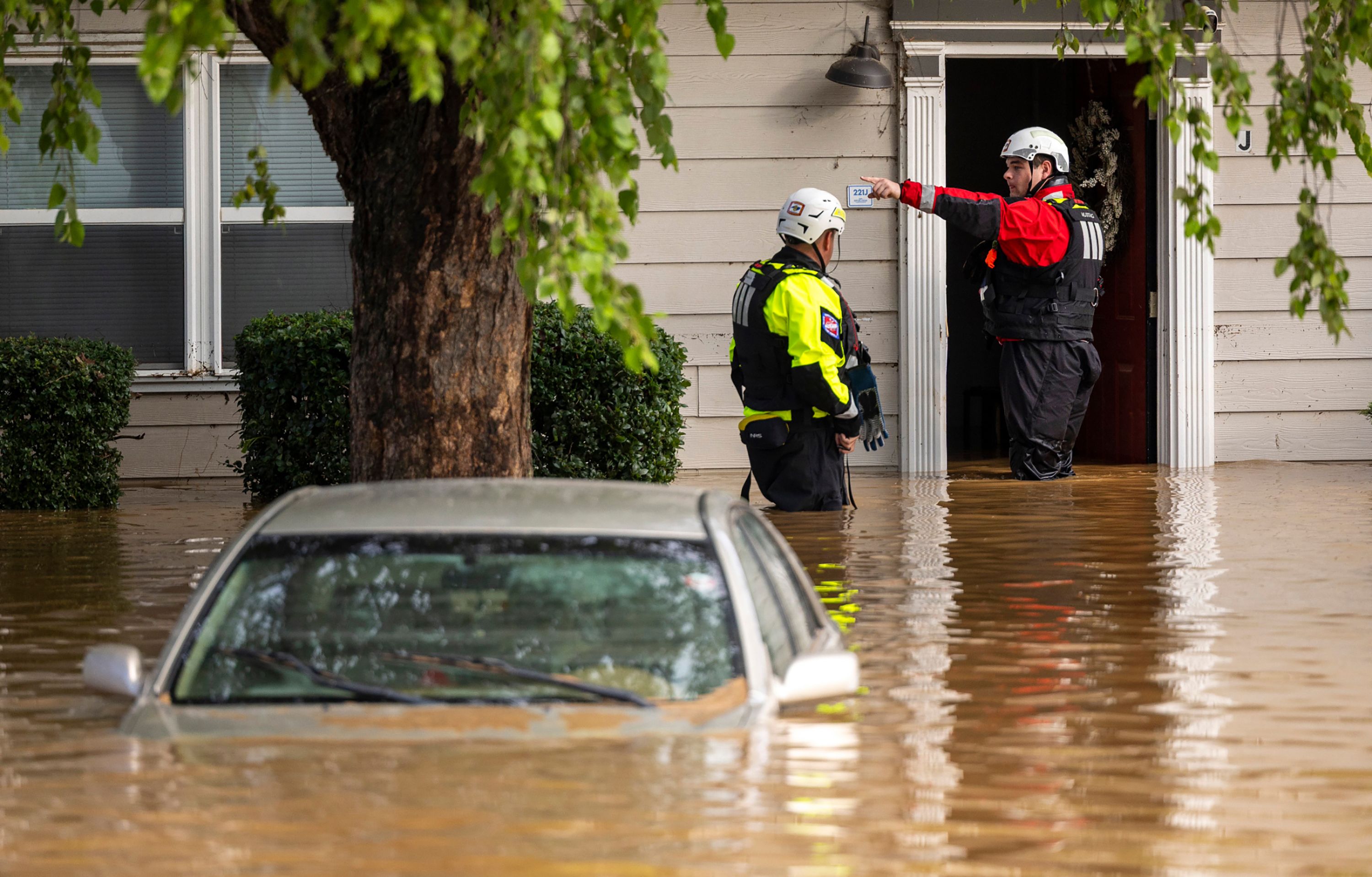 A water rescue unit with the Durham Fire Department knocks on doors along the Eno River in Durham after Tropical Storm Chantal. Muddy water is up to their thighs.