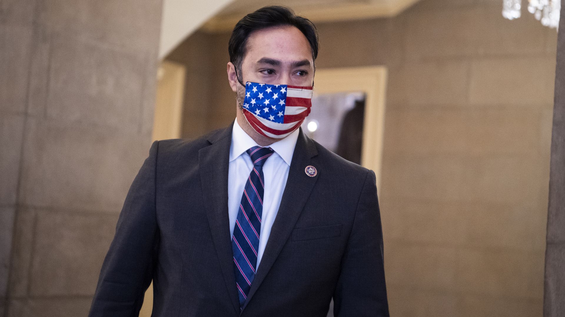 Rep. Joaquin Castro, wearing an American flag face mask, walks through Congress.