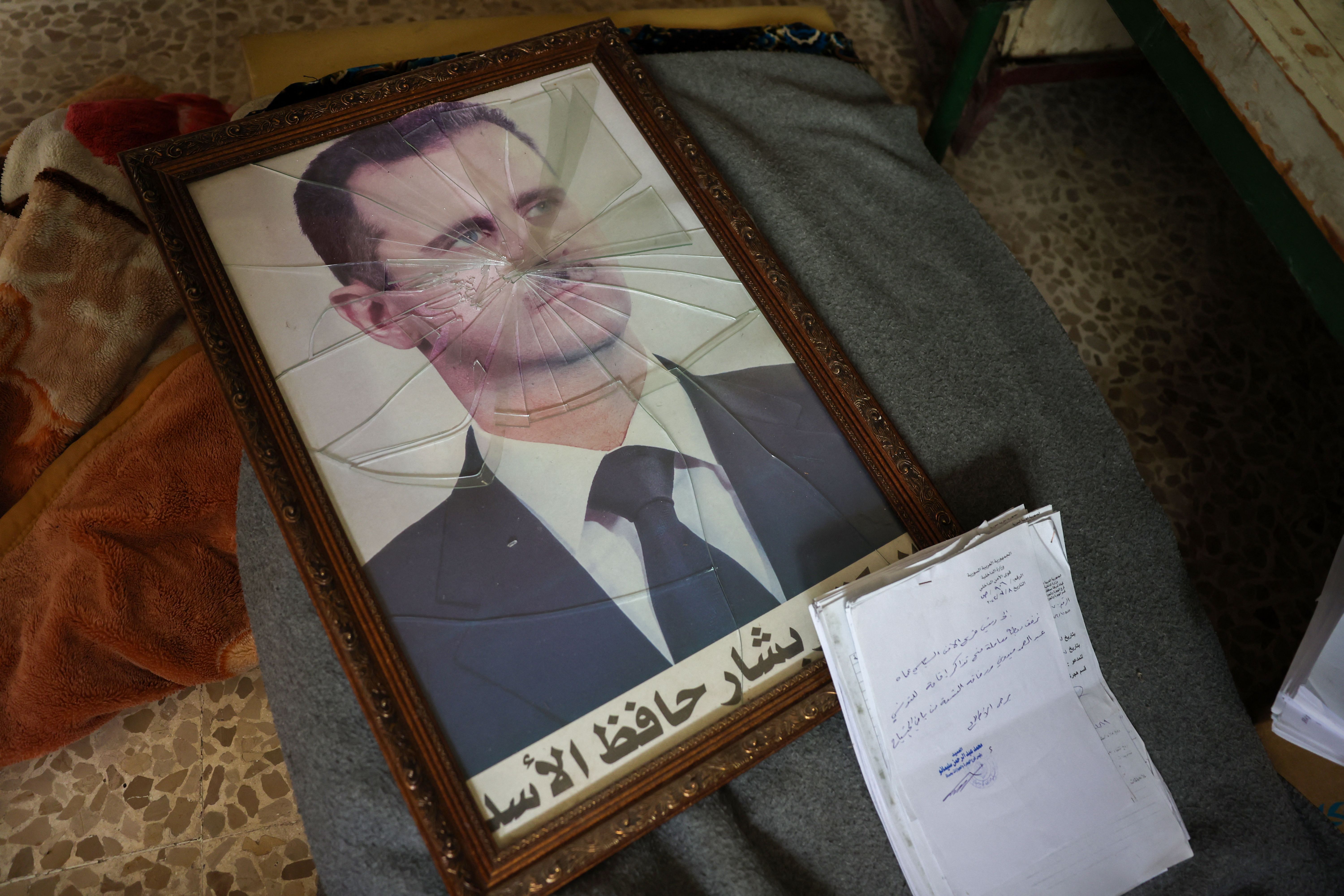 A portrait of Syrian President Bashar al-Assad is pictured with its frame broken, in a Syrian regime's Political Security Branch facility on the outskirts of the central city of Hama, following the capture of the area by anti-government forces, on December 7, 2024. Syria's embattled government said 
