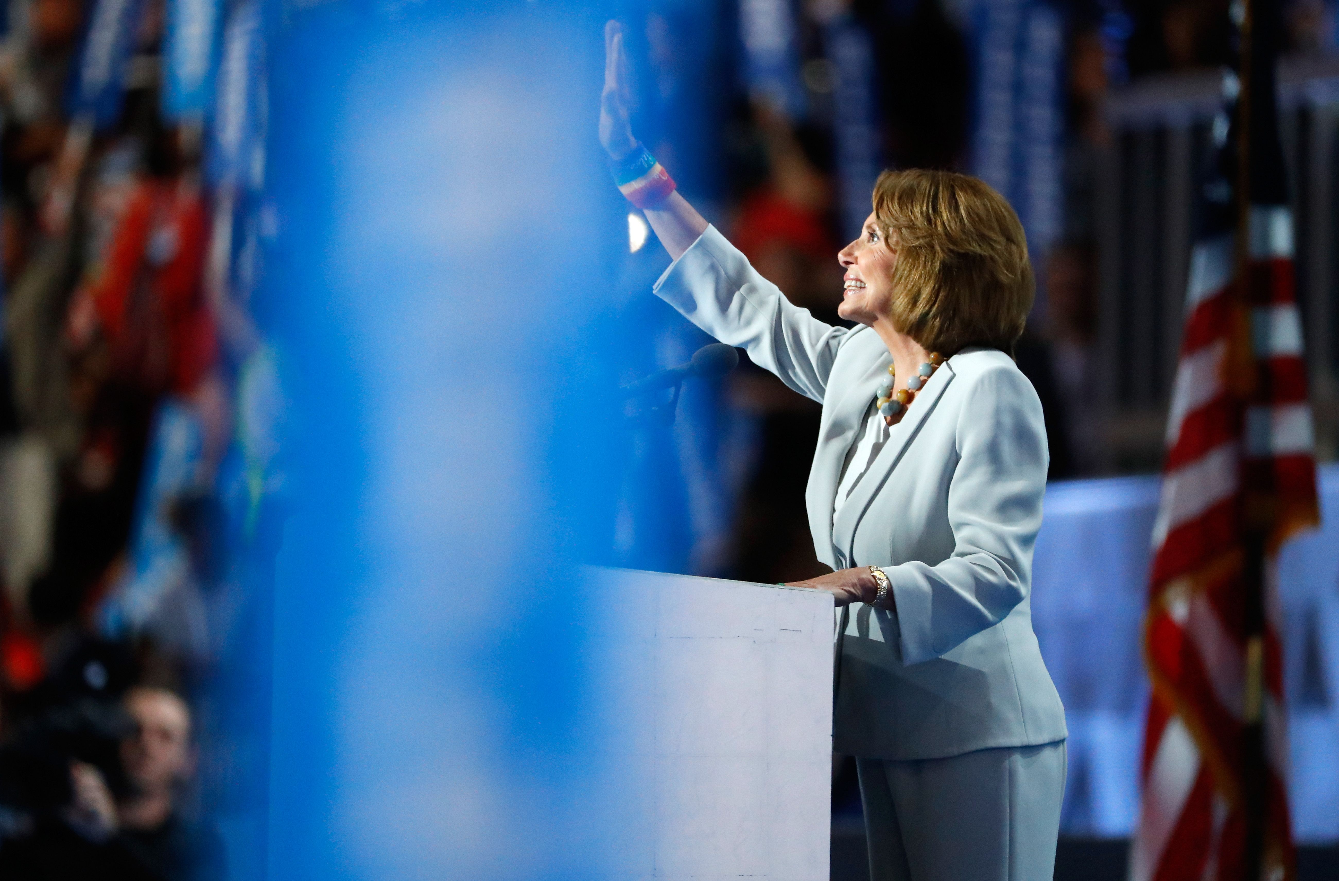 Nancy Pelosi, wearing a light blue suit, waves to the crowd at the 2016 Democratic National Convention.