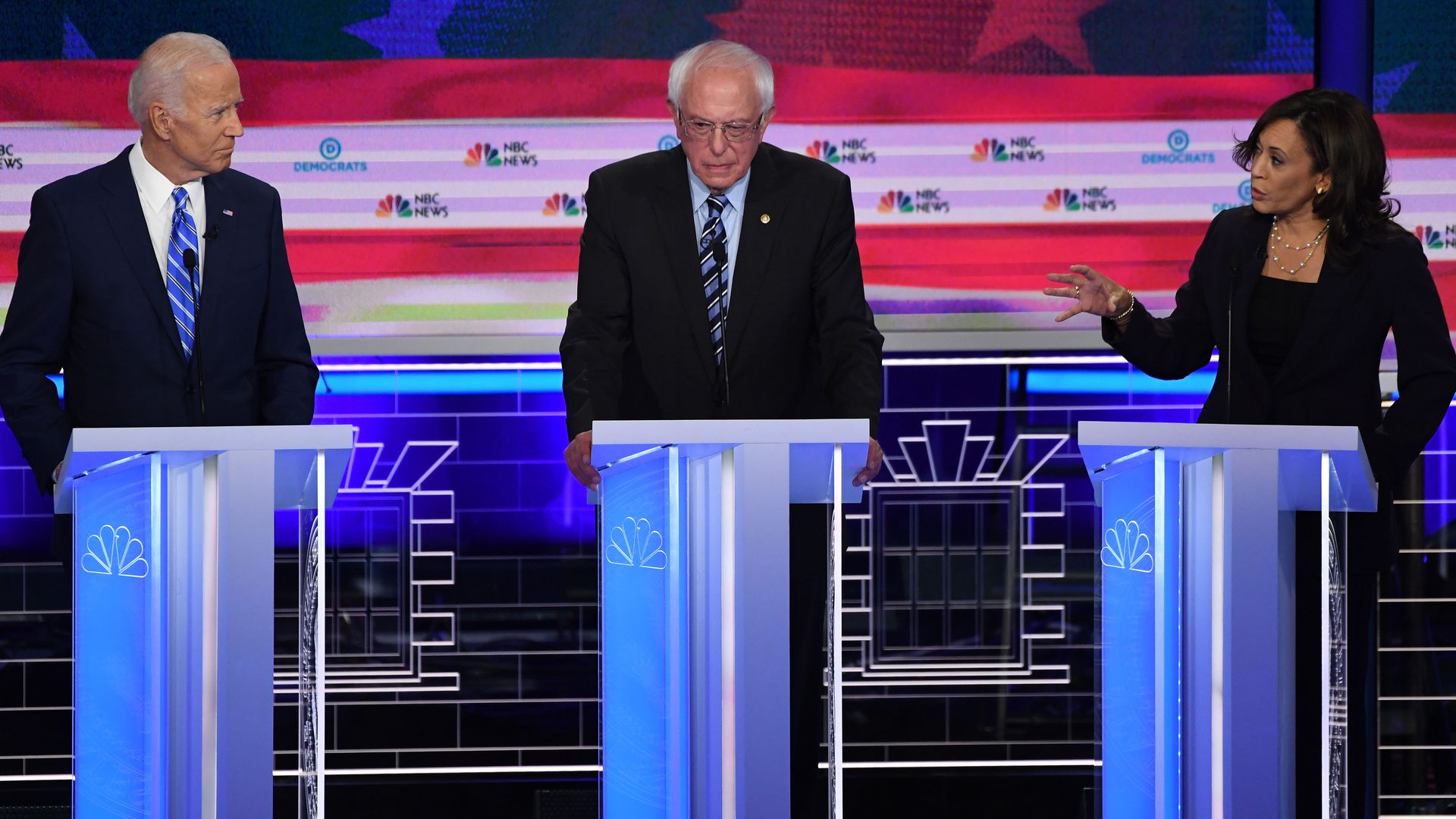 In this image, Bernie Sanders stands between Joe Biden and Kamala Harris.