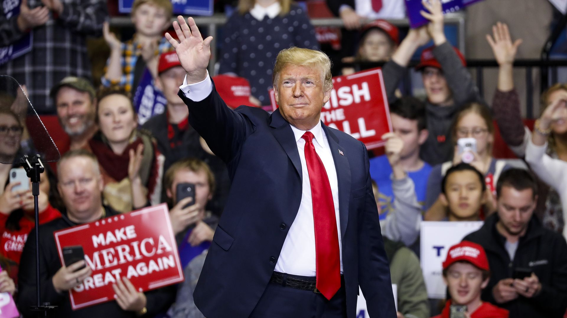 President Donald Trump waves while walking onto the stage at a MAGA rally