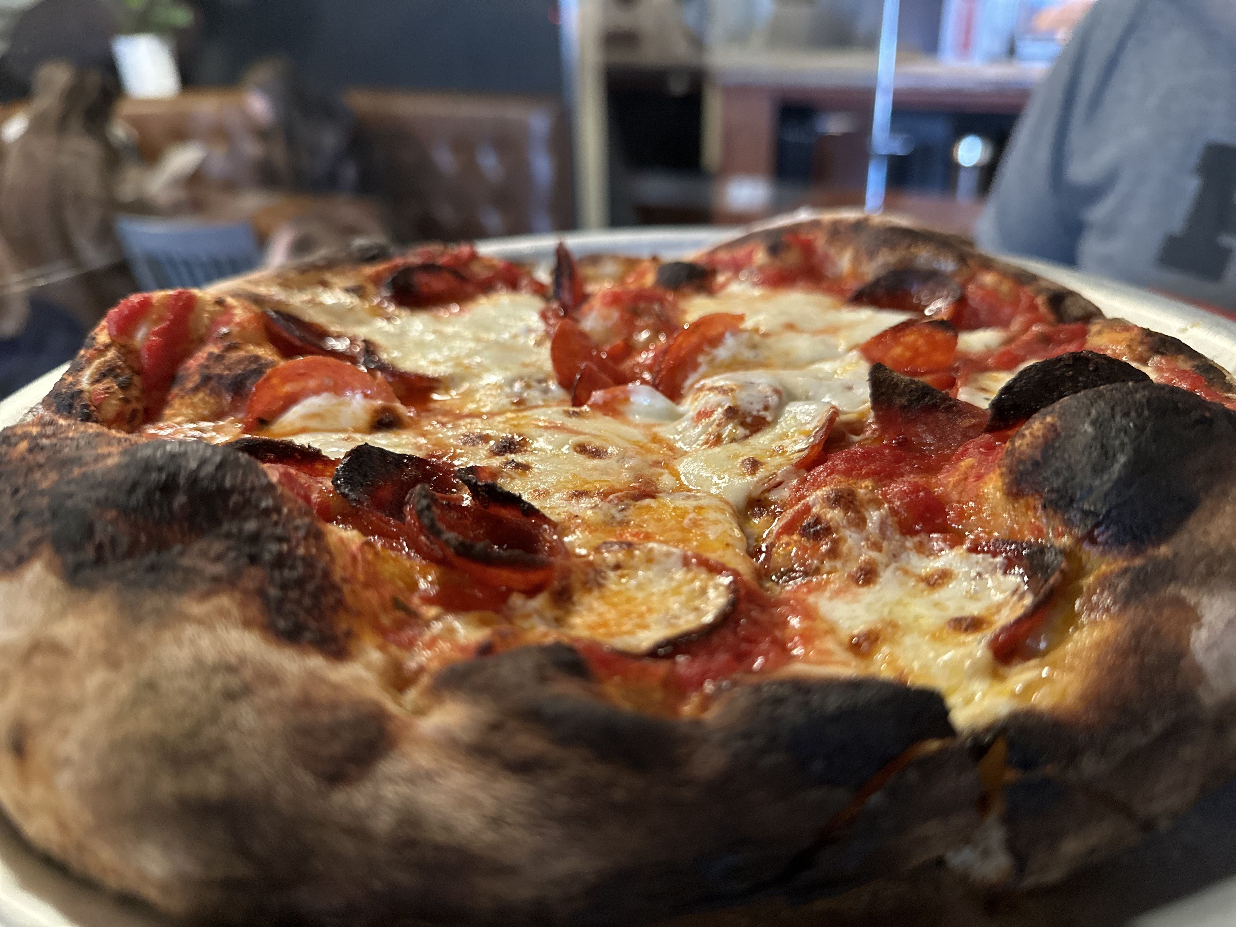 A close up of a pepperoni pizza pie with a charred, wood-fired crust at Picco in Boston.
