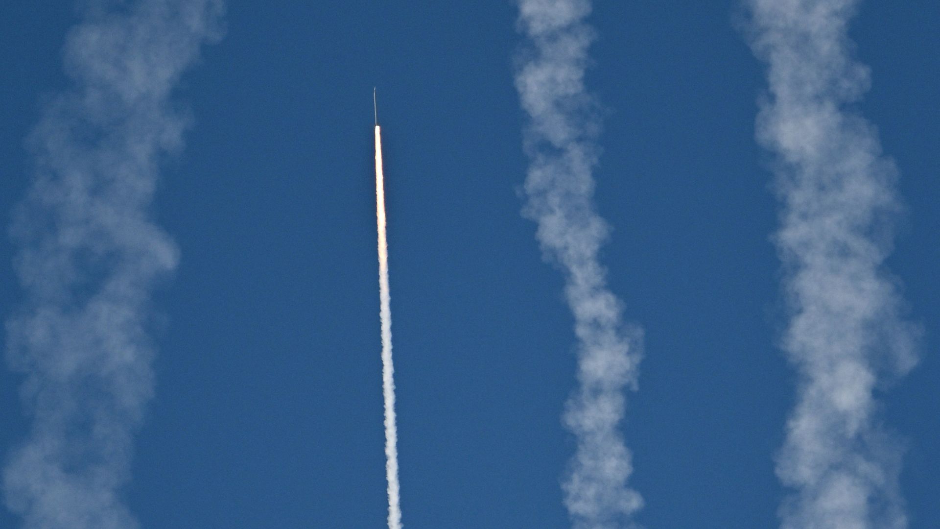 A Chinese rocket is fired into the air, as 2 smoke streams can be seen in the blue sky to the right and another to the left, as China's military conducts drills on Pingtan island, in eastern China's Fujian province, the closest point to Taiwan on Tuesday.