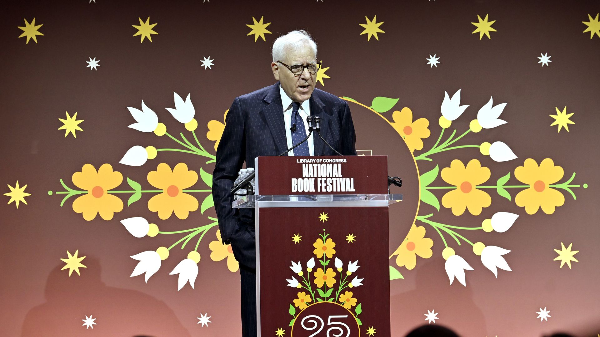 A man stands on a stage behind a podium that reads "National Book Festival."