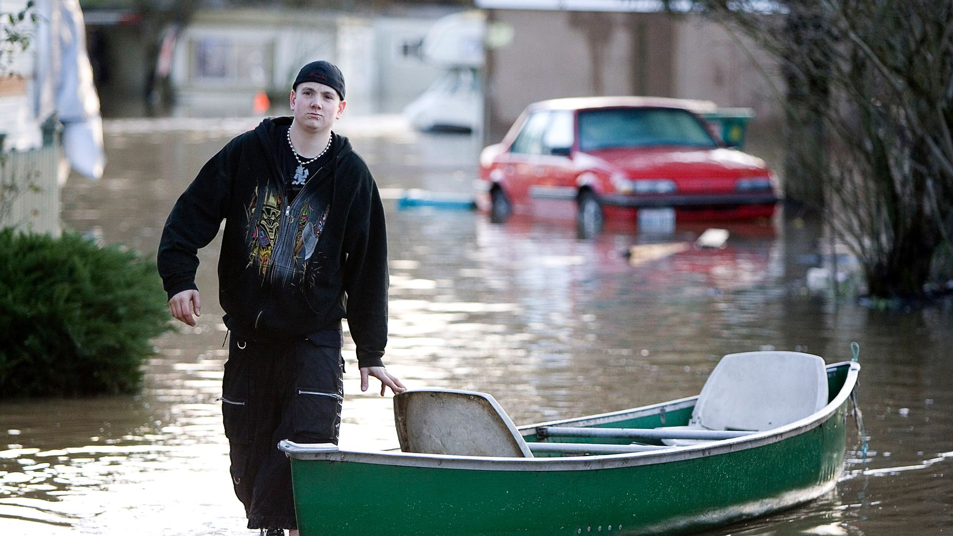 A teen pulls a canoe through flooded streets in Washington state. 