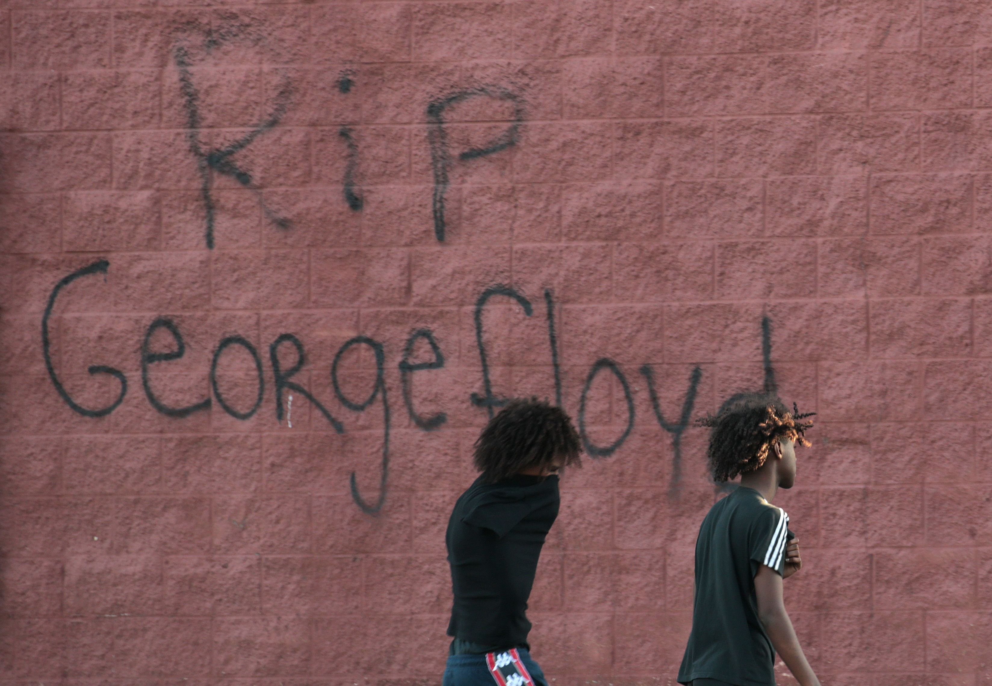 Two men walk past a wall that has "RIP George Floyd" written on Wednesday in St. Paul, Minnesota. Photo: Scott Olson/Getty Images