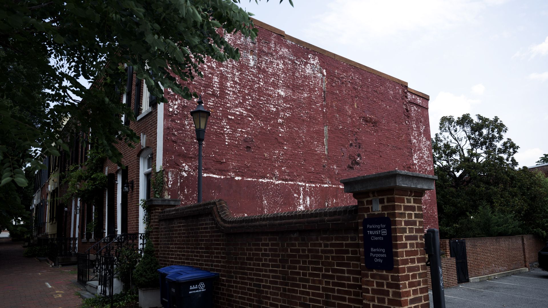 An photo showing a large brick wall on the side of a brick rowhouse. 