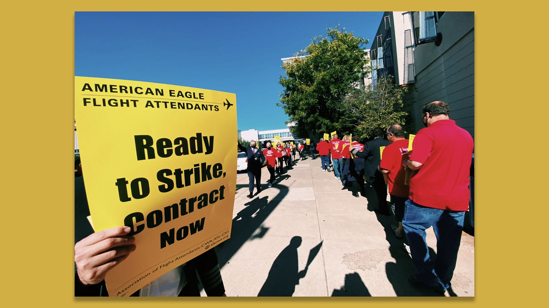A person holds a yellow sign that reads, "Ready to Strike, Contract Now," outside the Philadelphia International Airport. 