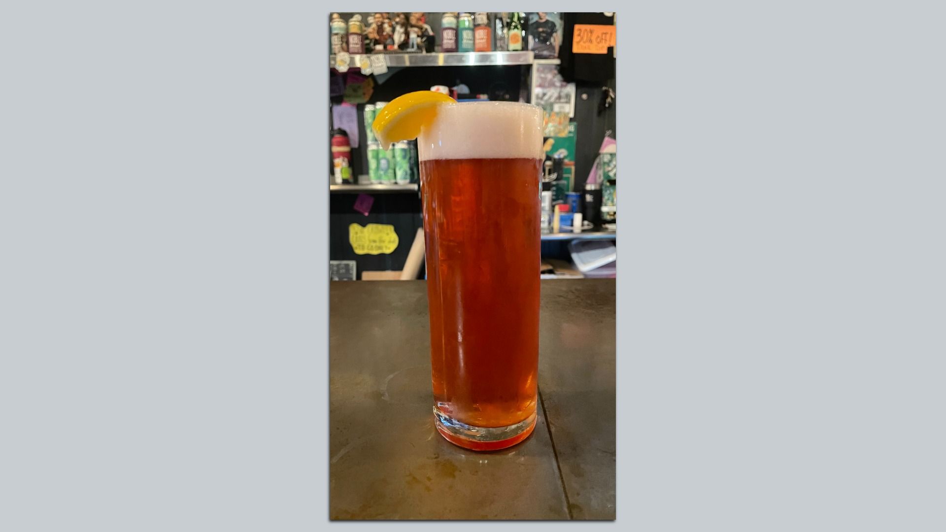 A beer with a lemon wedge on glass