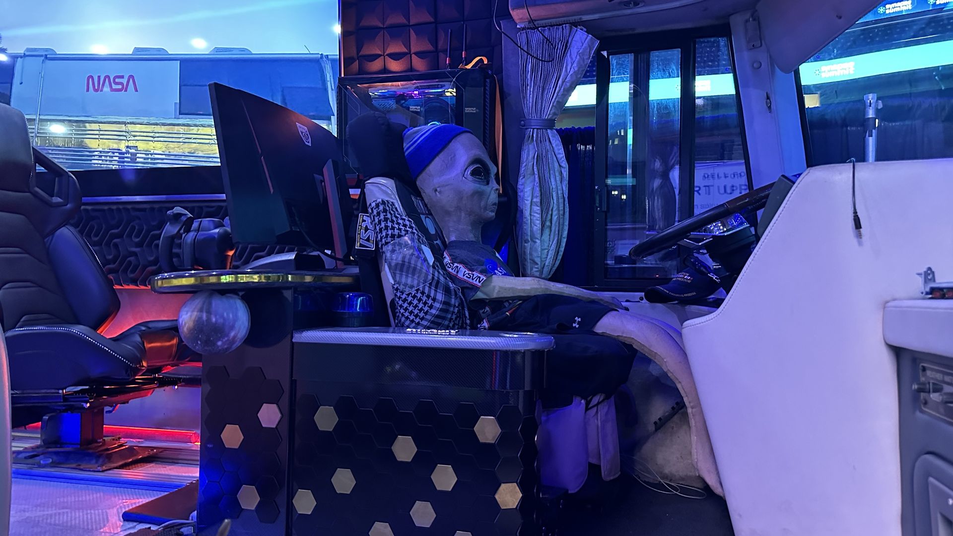 A toy alien in the driver's seat of a NASA-branded charter bus inside Amalie Arena.