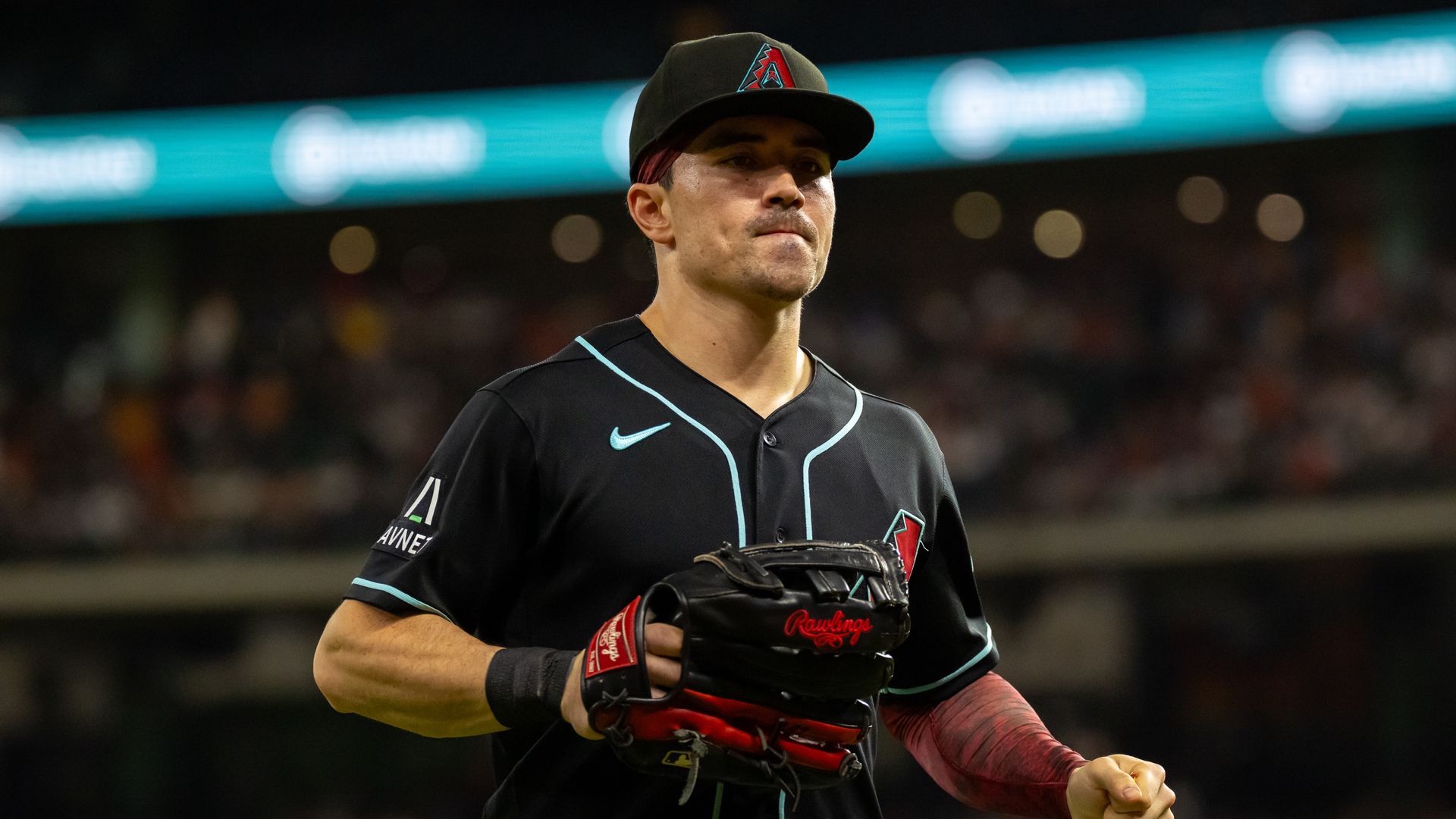 Diamondbacks player Corbin Carroll runs while in a black jersey with teal trim and a black glove.