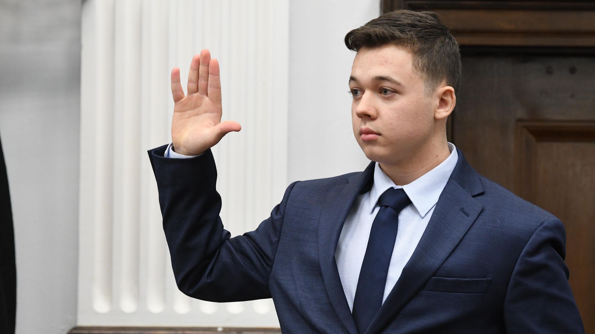 Photo of Kyle Rittenhouse raising his right hand in court.
