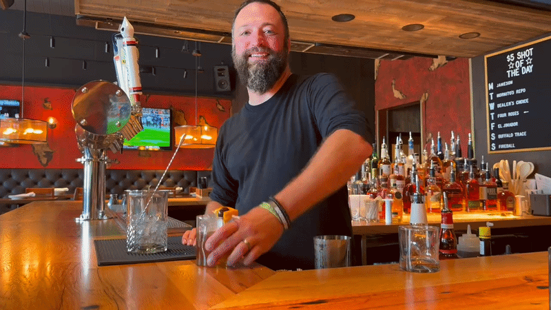 A bartender pushing a finished drink across the bar