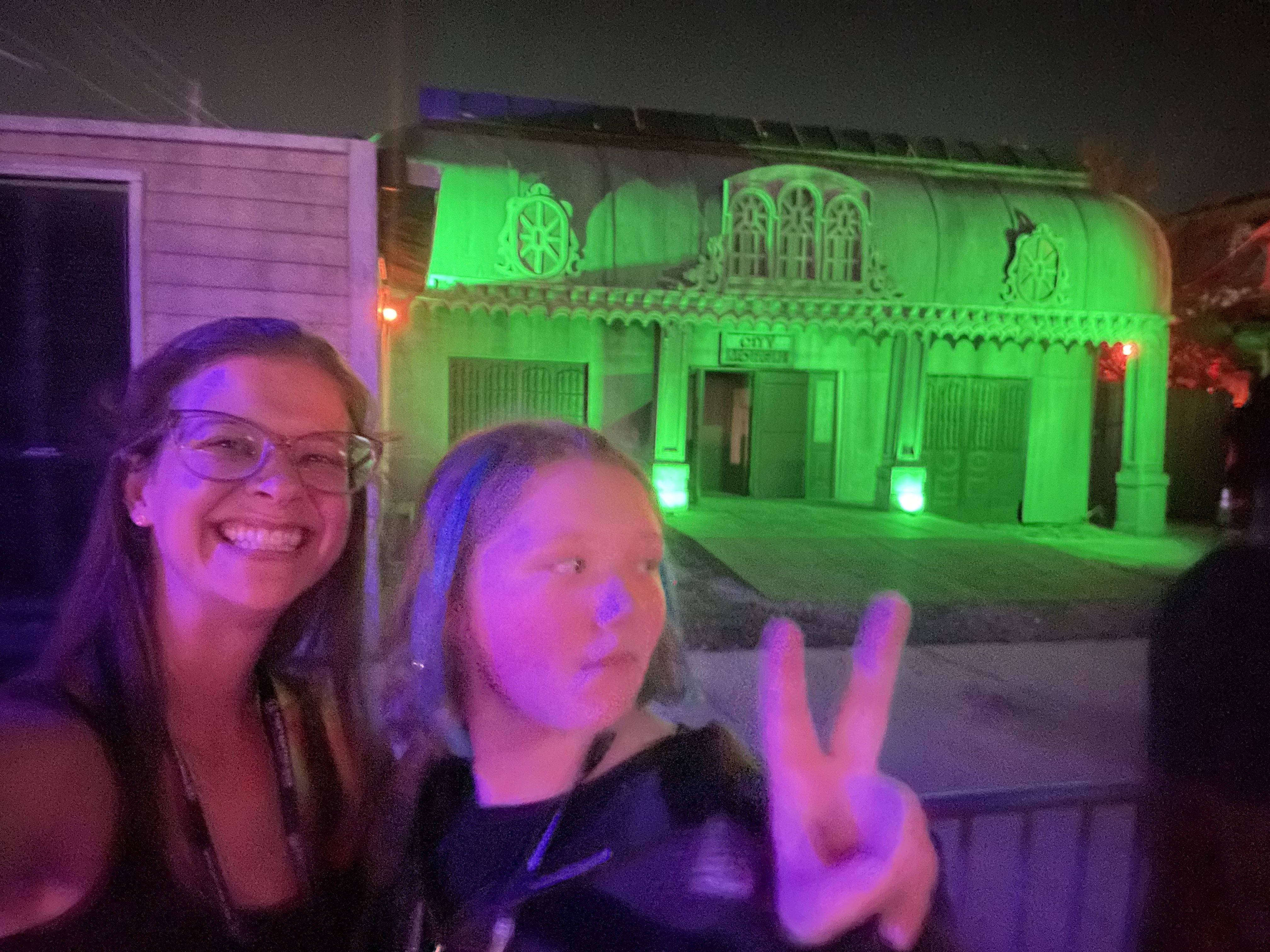 A selfie of two people, one looking off-camera, as she flashes a peace sign.