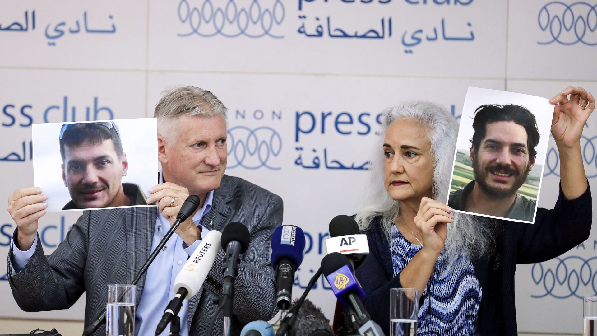 Marc and Debra Tice hold up photos of their son Austin at a press conference.