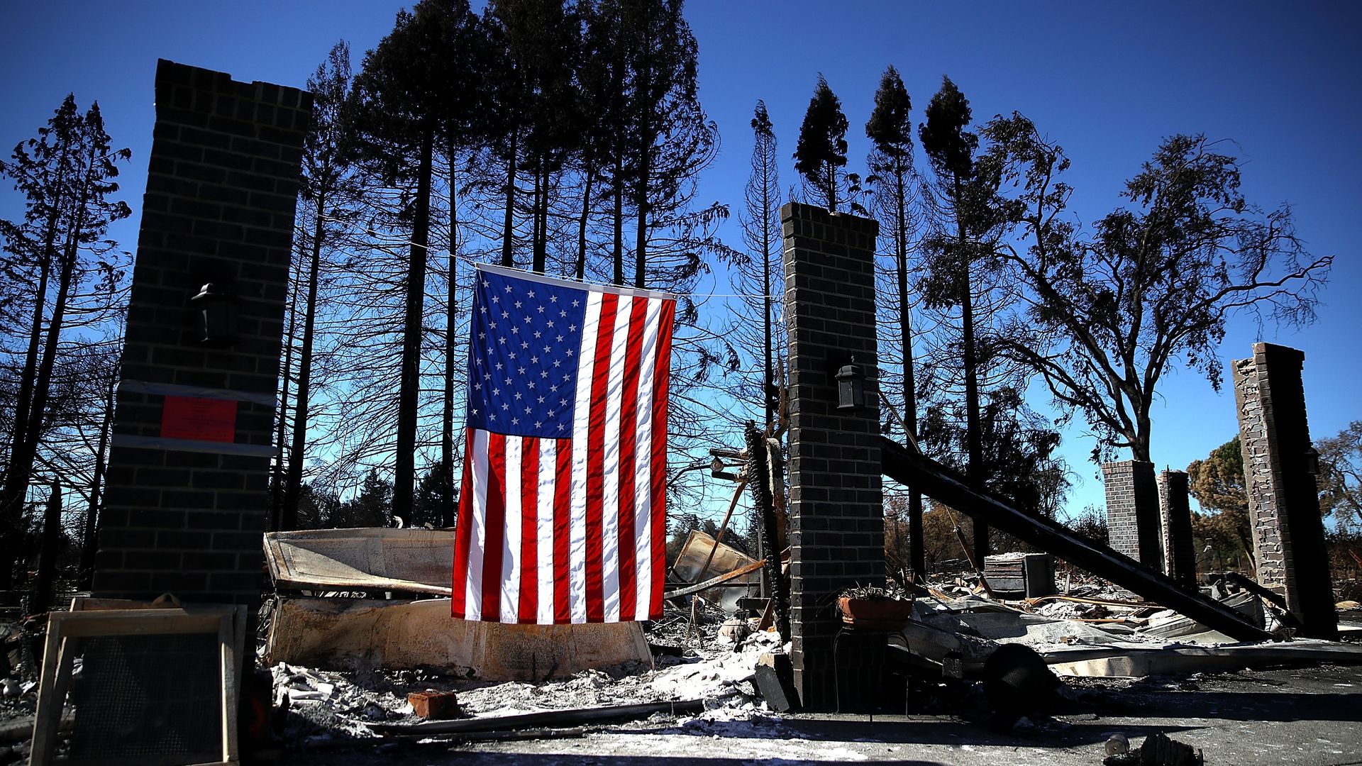 An American flag hangs in front of a home that was destroyed by a wildfire in California. 