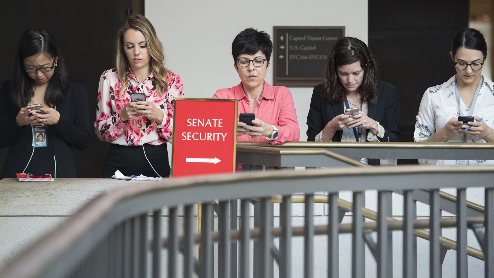 A row of people standing and using their phones