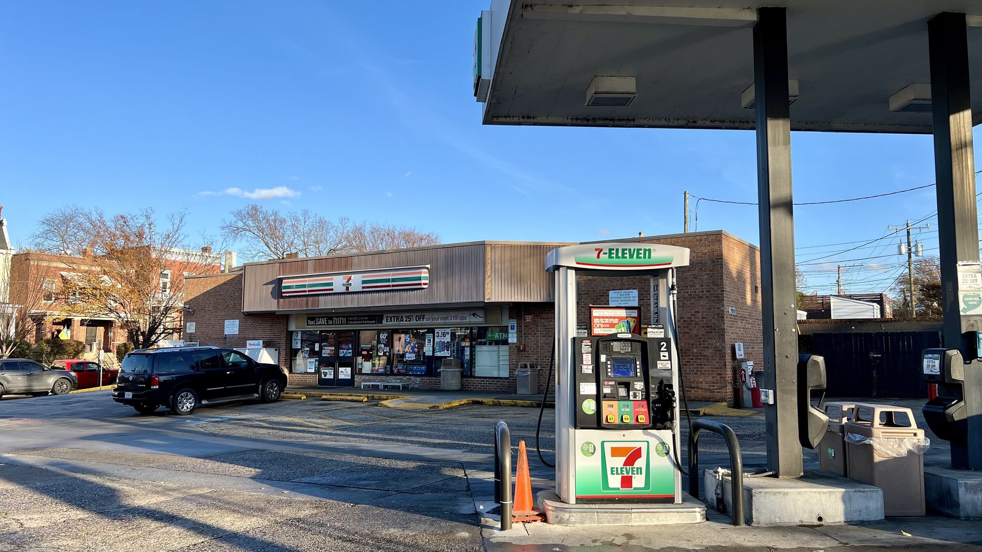 A 7-eleven gas station with the gas pump on the right and the building in the back next to houses