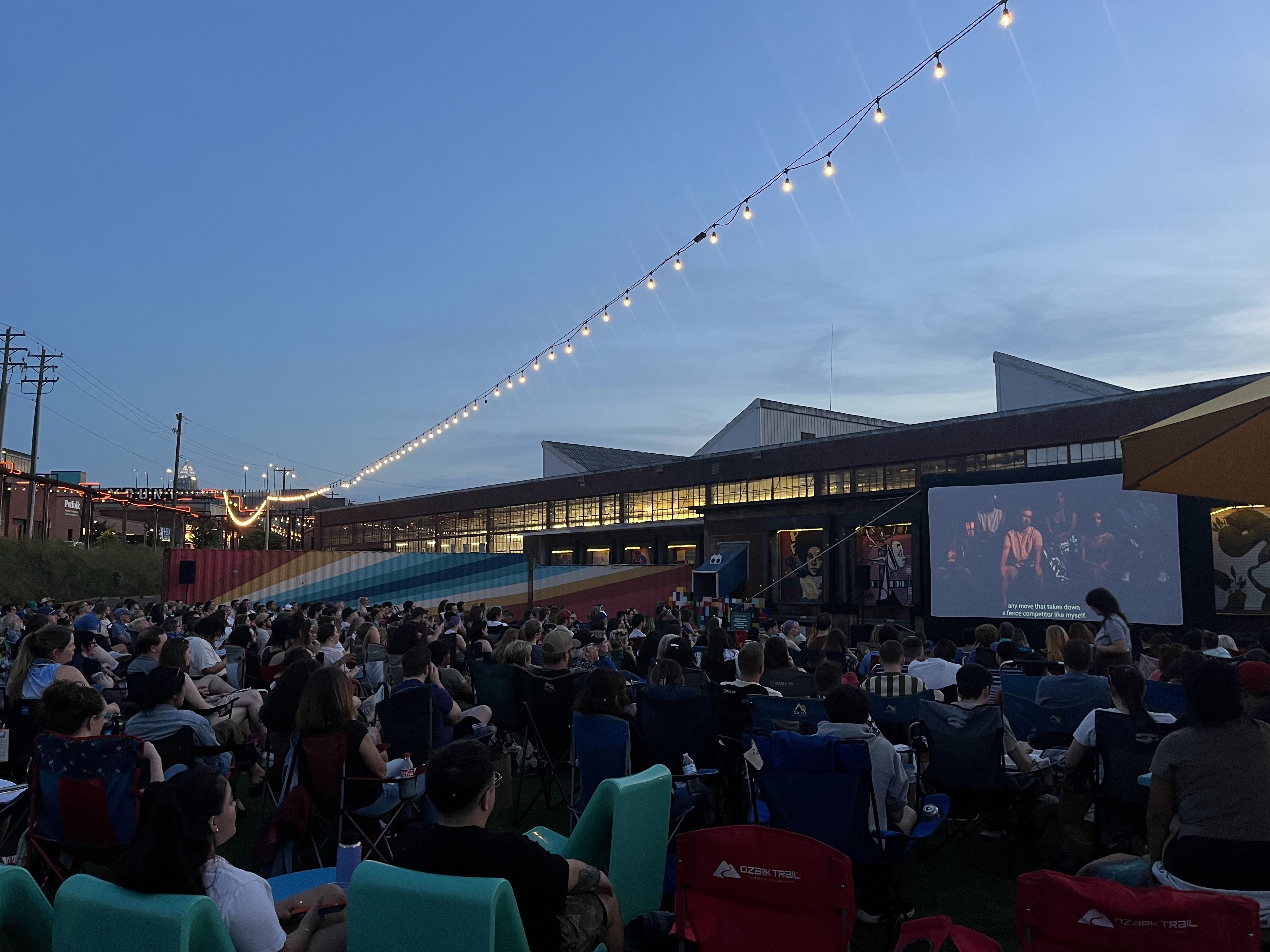 crowd of people watching a projected screen outside