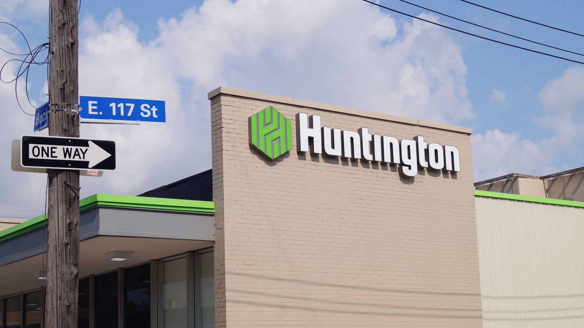 Photo of exterior of a Huntington bank branch behind E. 117th St sign in Cleveland. 