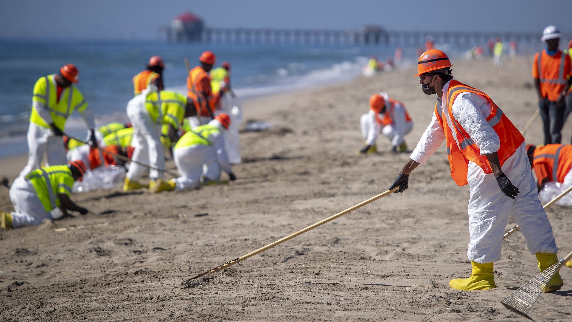 Crews clean up the oil spill at Huntington State Beach in Huntington Beach Sunday.