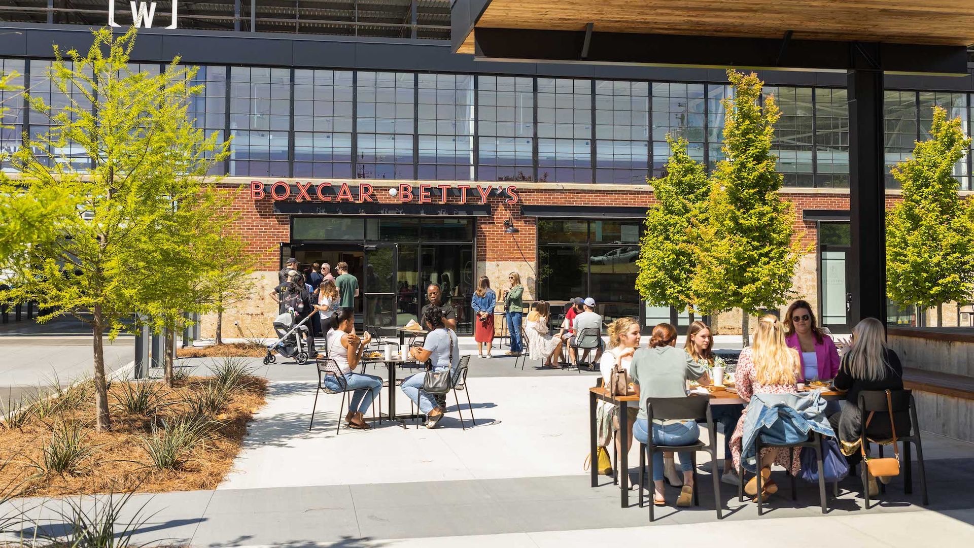 A photo of people sitting outside of a sleek mixed-use development on a sunny day