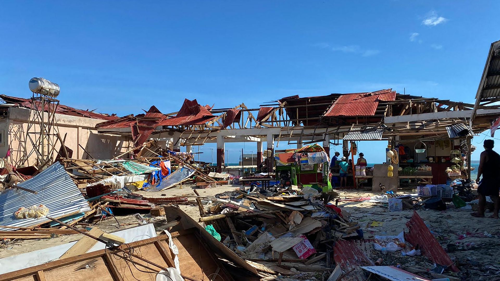 residents stand next to a destroyed market building after typhoon rai