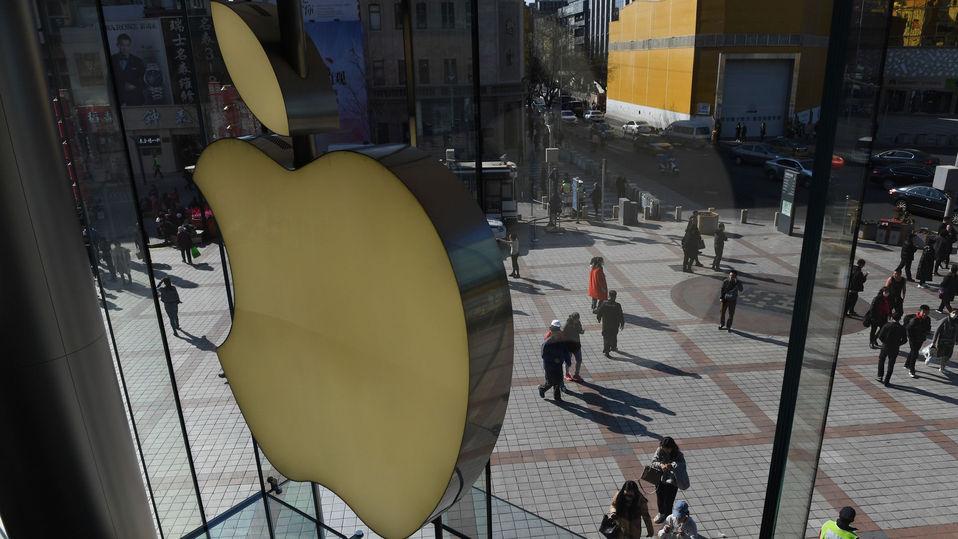 In this image, the Apple logo is displayed over a city walkway with a few pedestrians. 