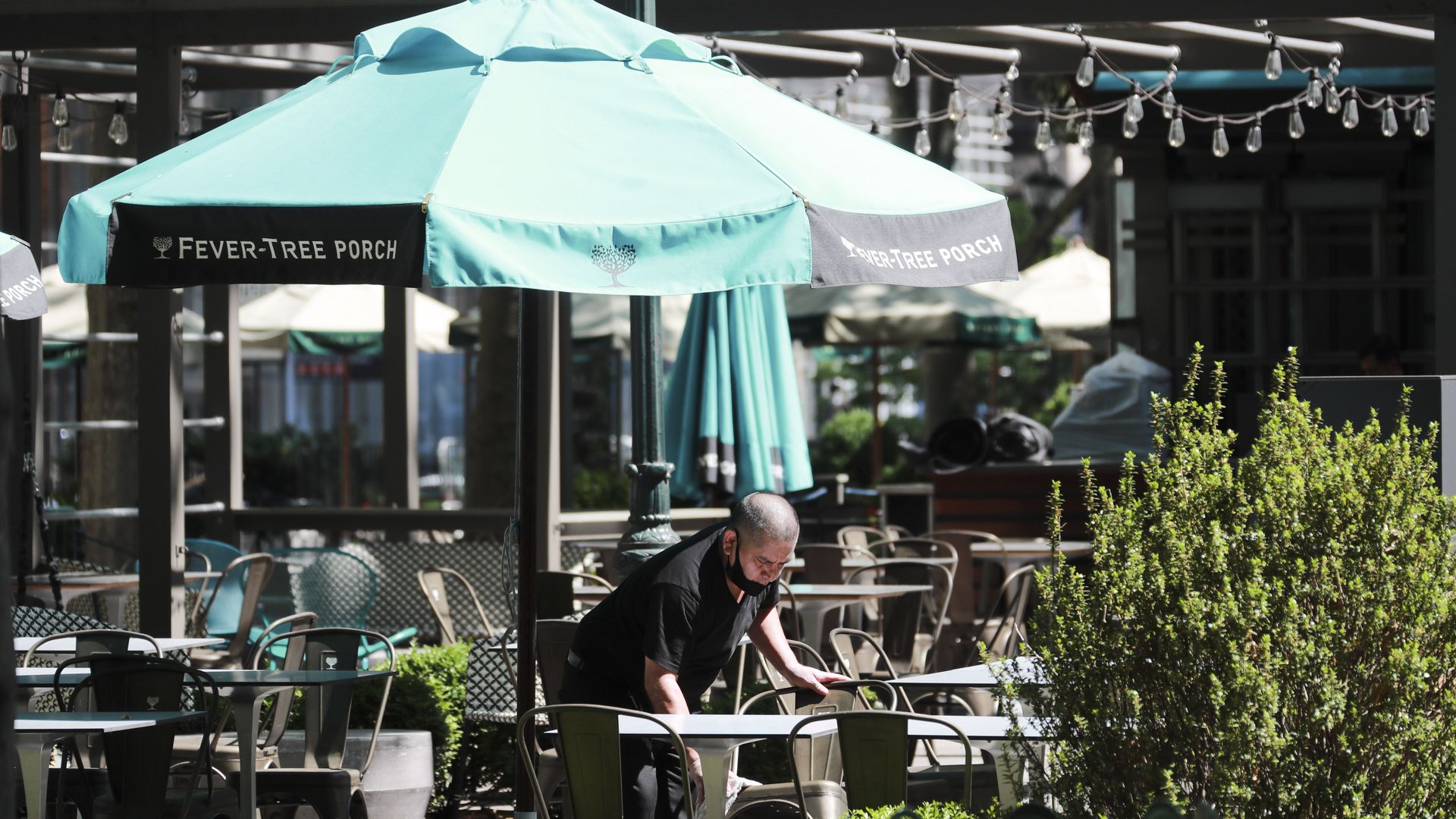 A staff member wearing a mask sets tables at a restaurant in New York, the United States, June 22, 2020