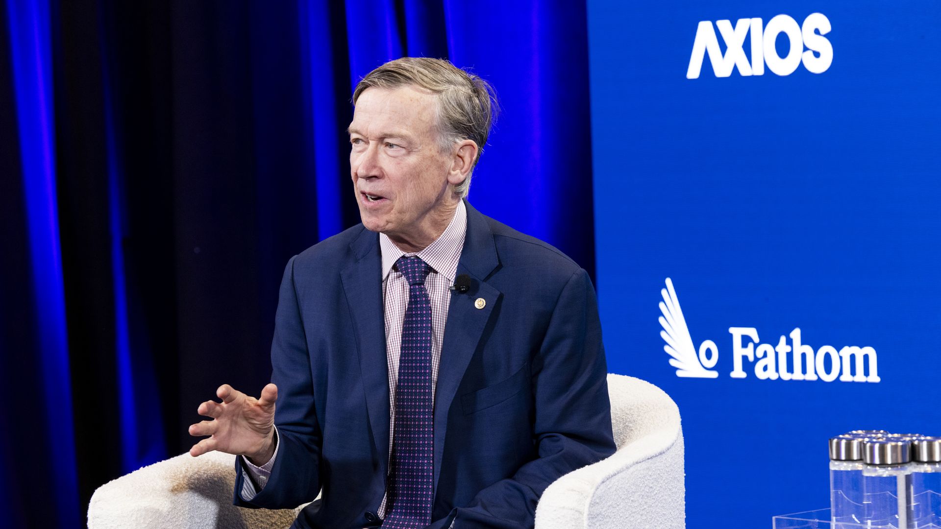 Sen. John Hickenlooper sitting on the Axios stage.