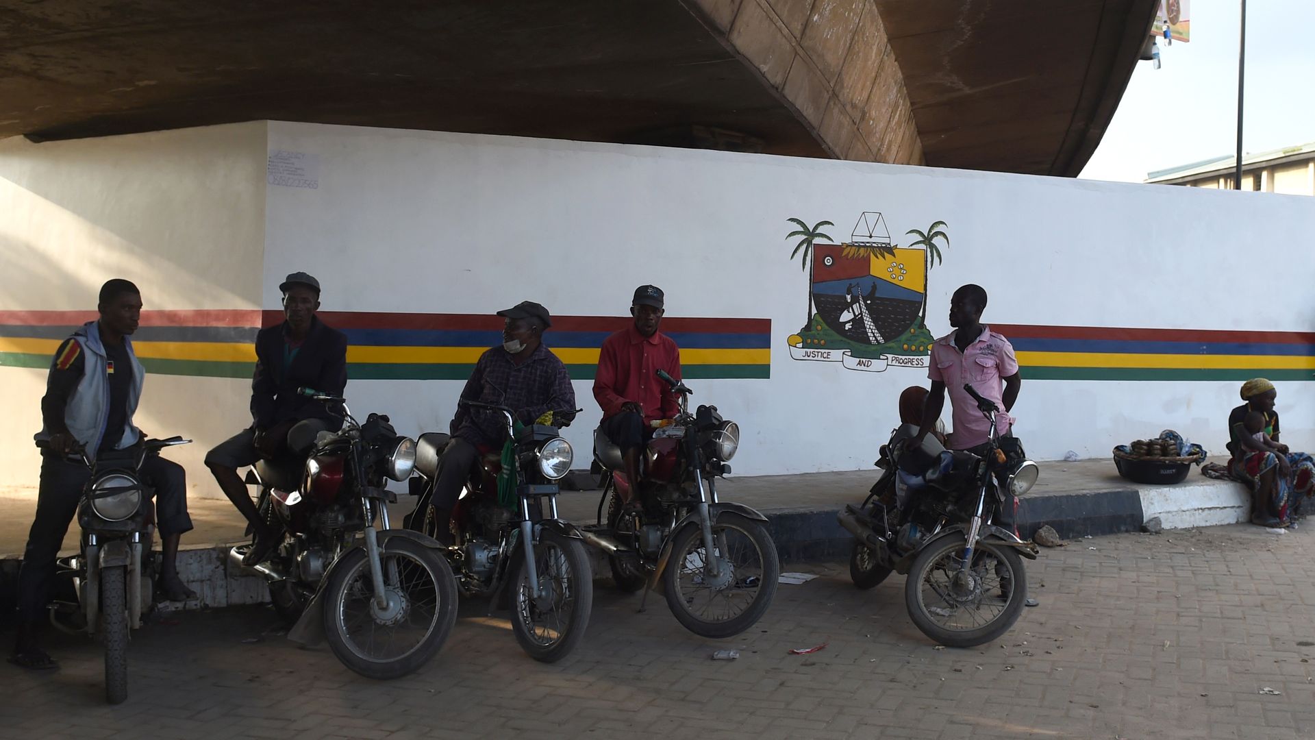 motorbike taxis waiting for passengers in the shade under an overpass