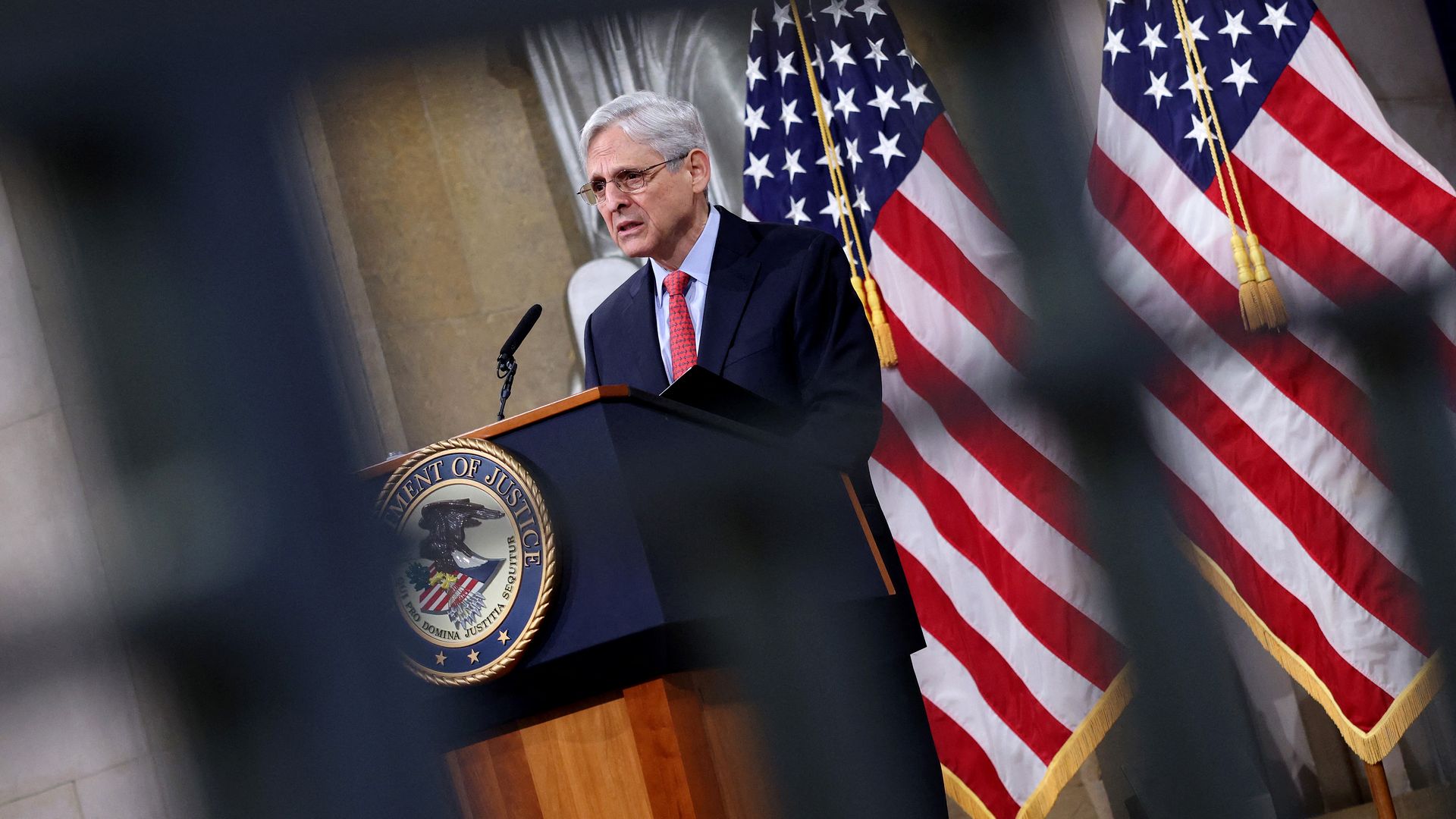 Photo of Merrick Garland speaking from a podium with the American flag behind him