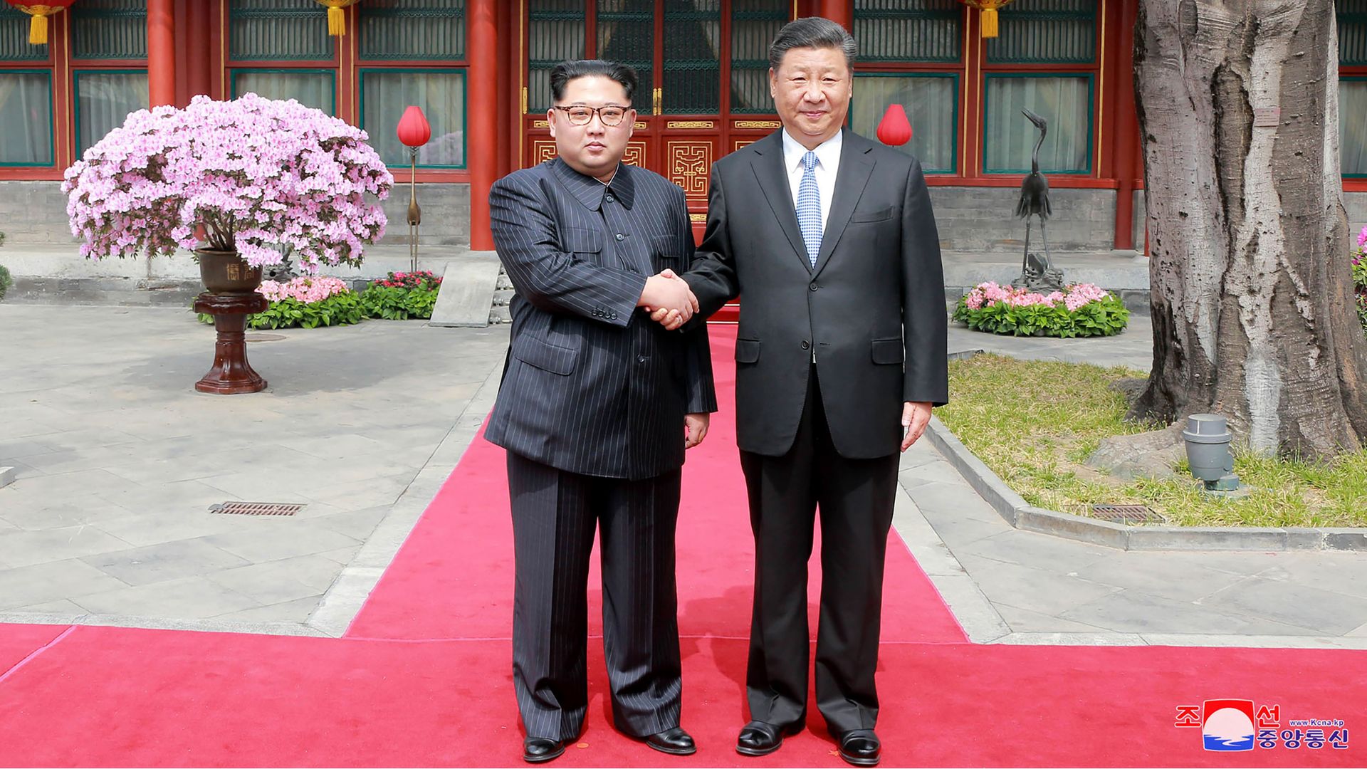 Kim Jong-un and Xi Jinping are shaking hands in the middle of the photo.