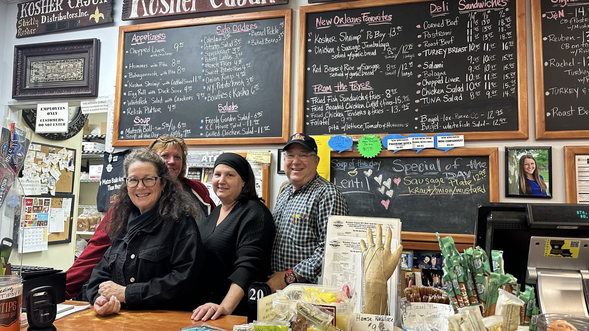 Photo shows people at the counter with a menu board behind them.