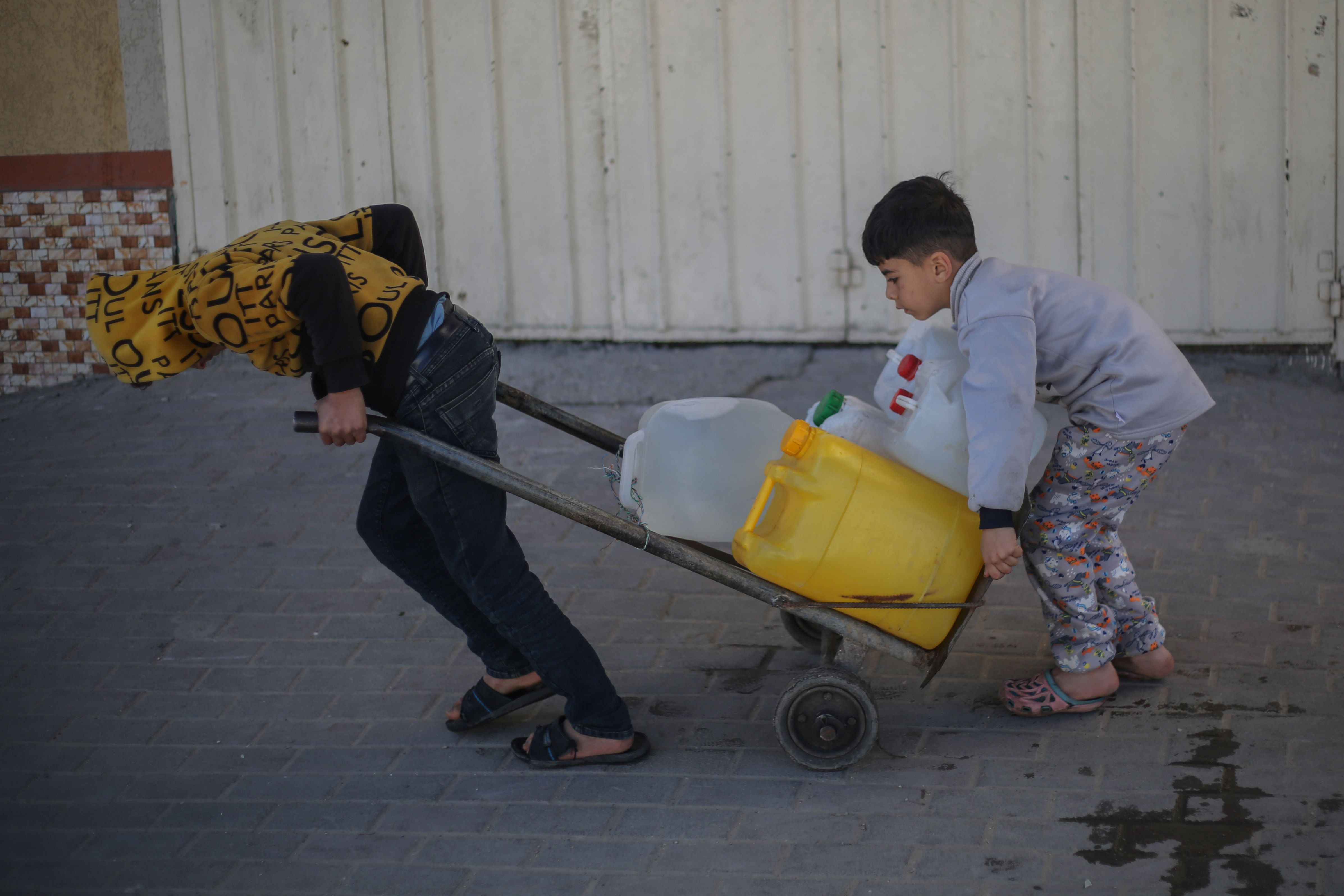 Palestinian children collect water from an aid station in Rafah, Gaza, yesterday. Photo: Ahmad Hasaballah/Getty Images