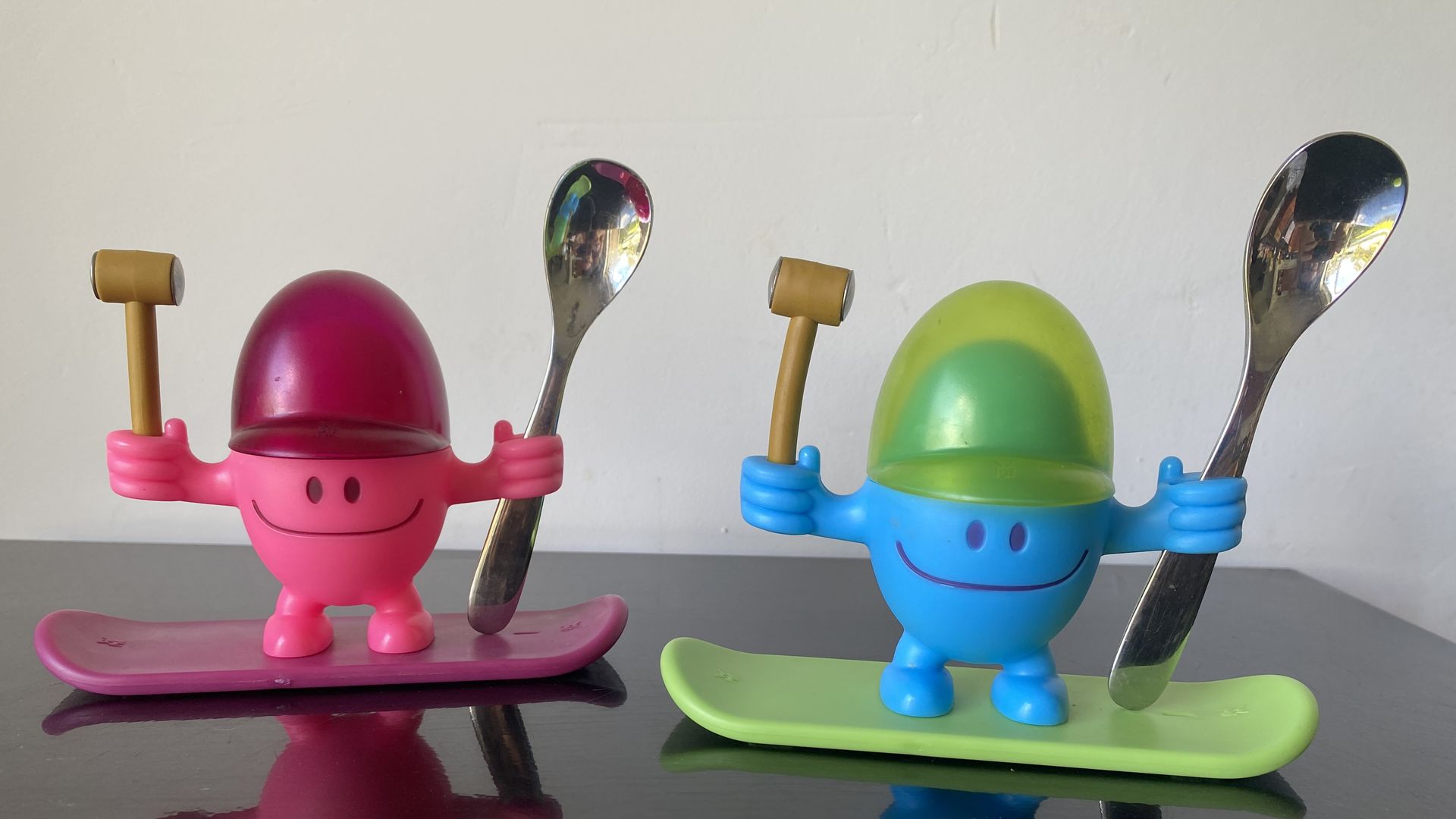 A pink egg-shaped character holds a spoon and mallet, as does a blue one.