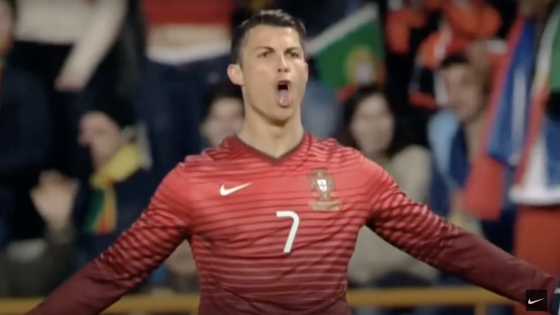 Soccer star Cristiano Ronaldo in a red jersey on the field with his arms extended