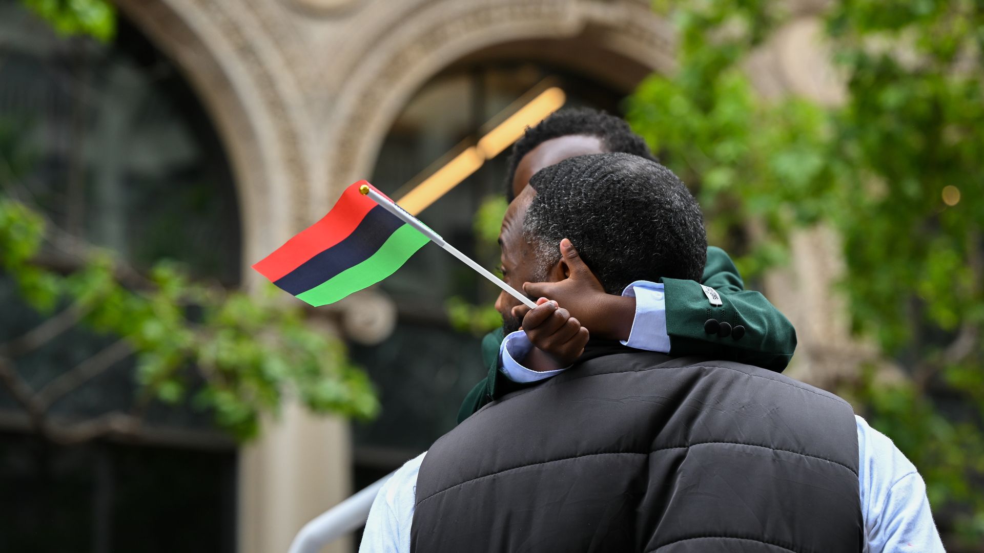 child with parent holding juneteenth flag