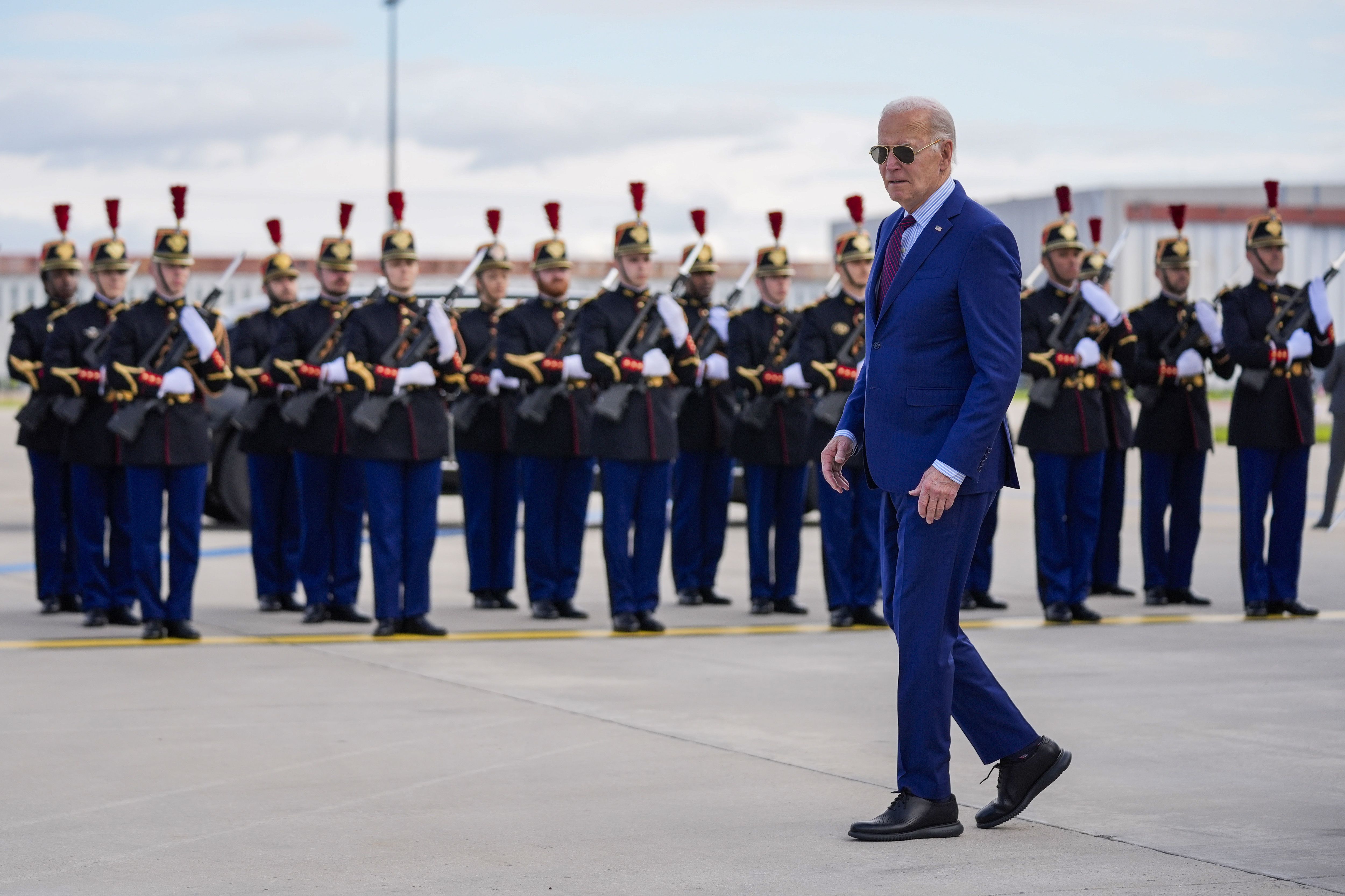 President Biden walks next to a French honor guard after arriving in Paris yesterday morning.