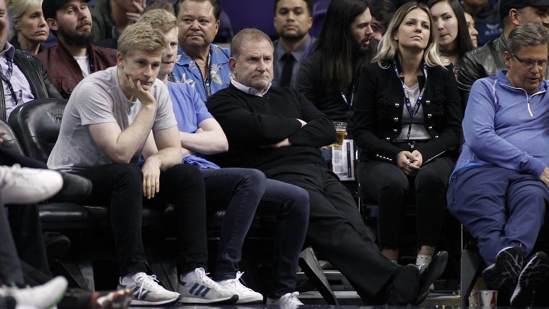 A group of people sit on a basketball court side line.