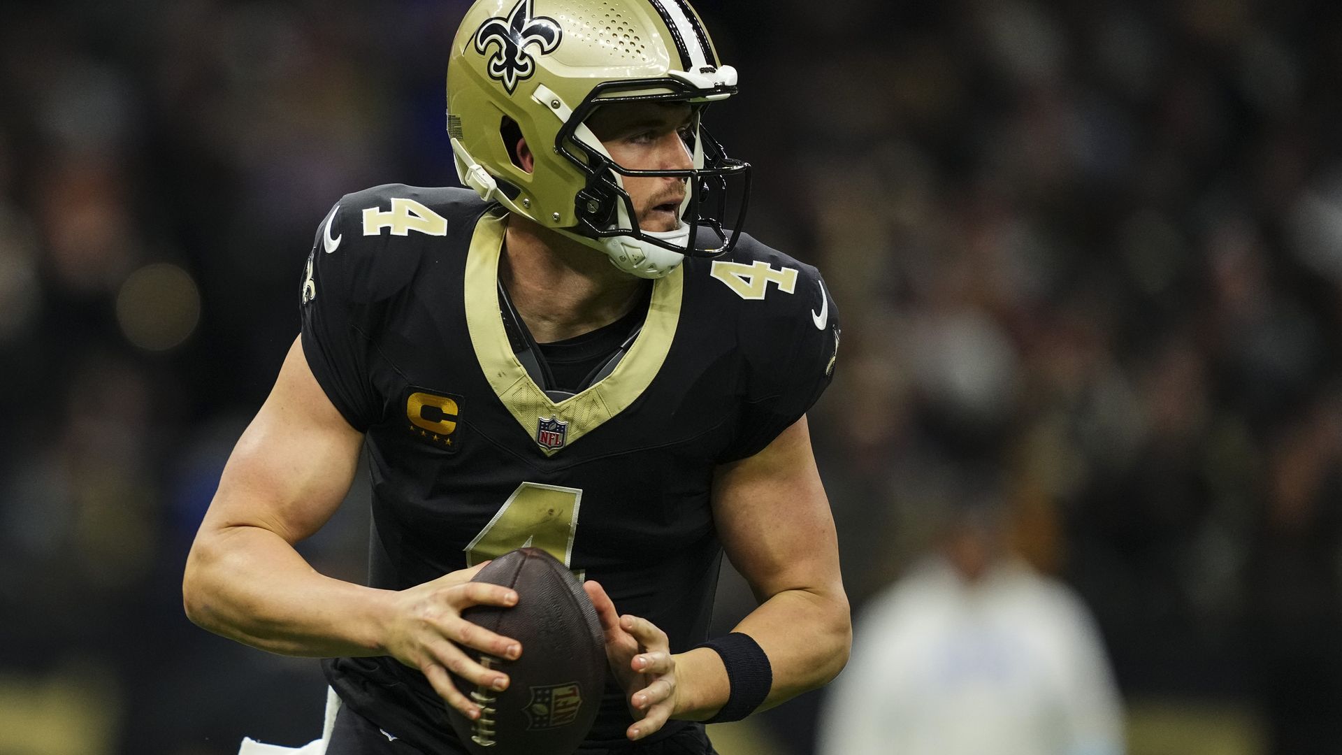 Photo shows Derek Carr in a black and gold Saints uniform with a football.