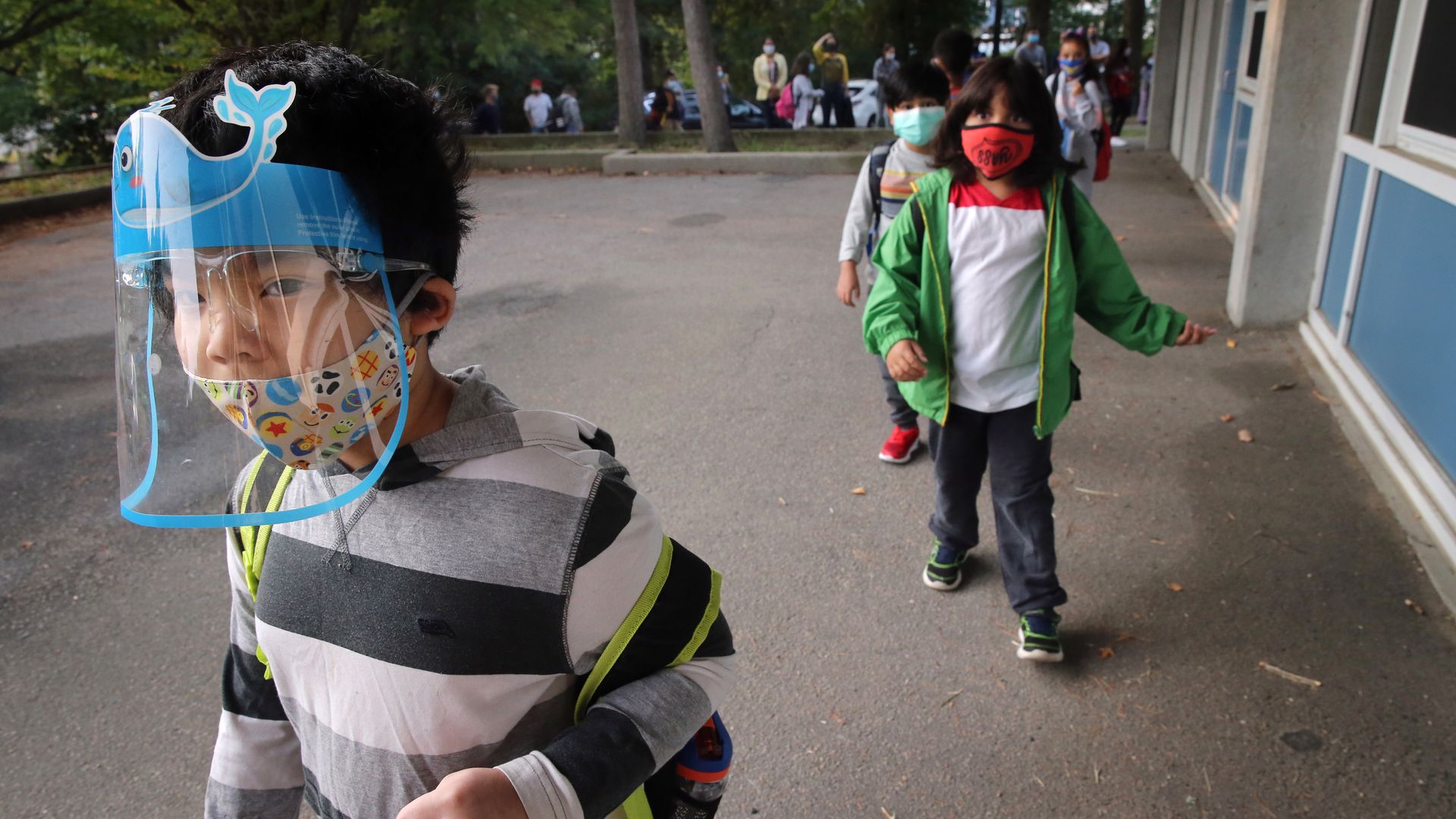 Photo of young students wearing masks walking to school