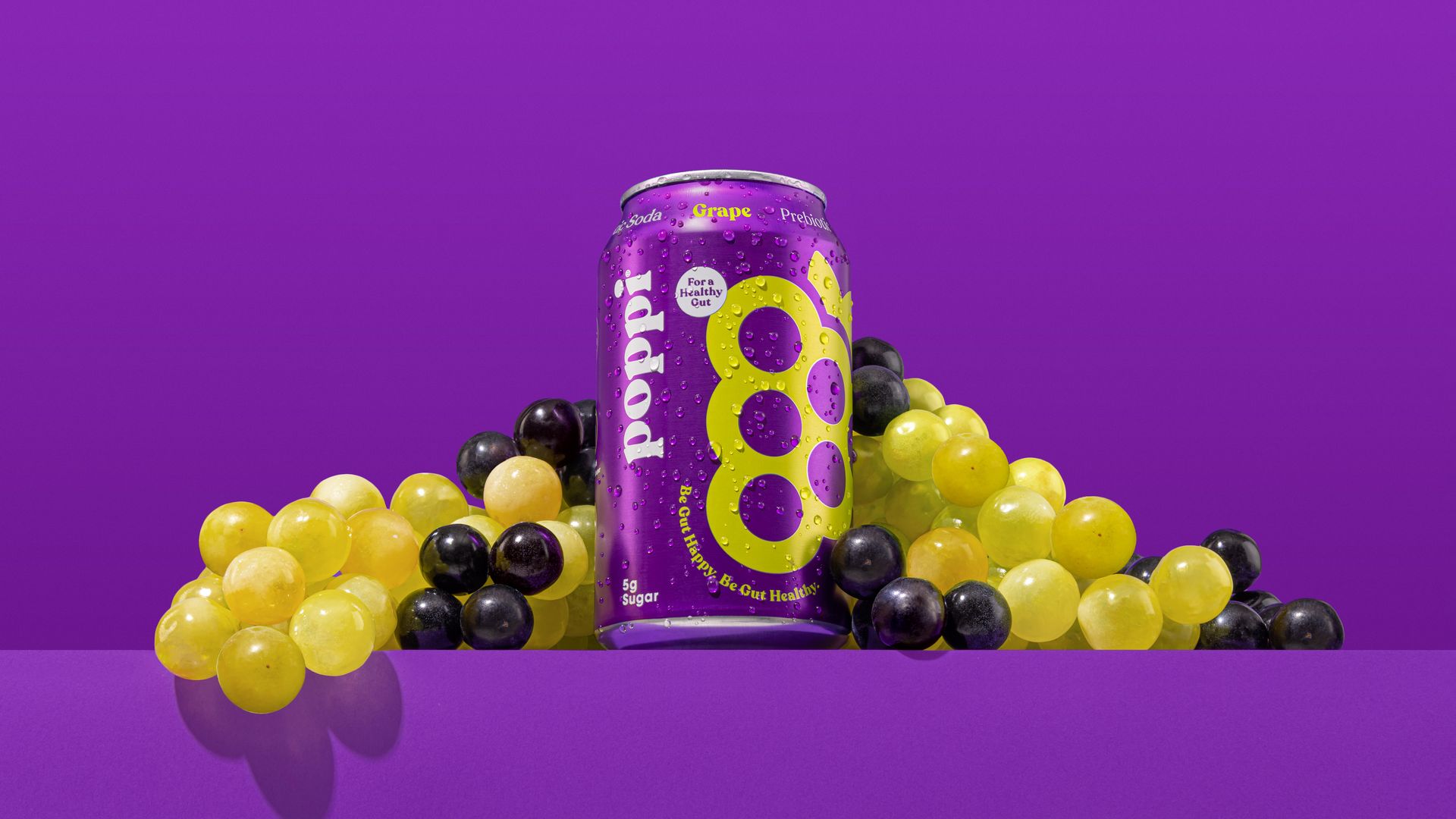 A can of Poppi grape-flavored soda surrounded by grapes.