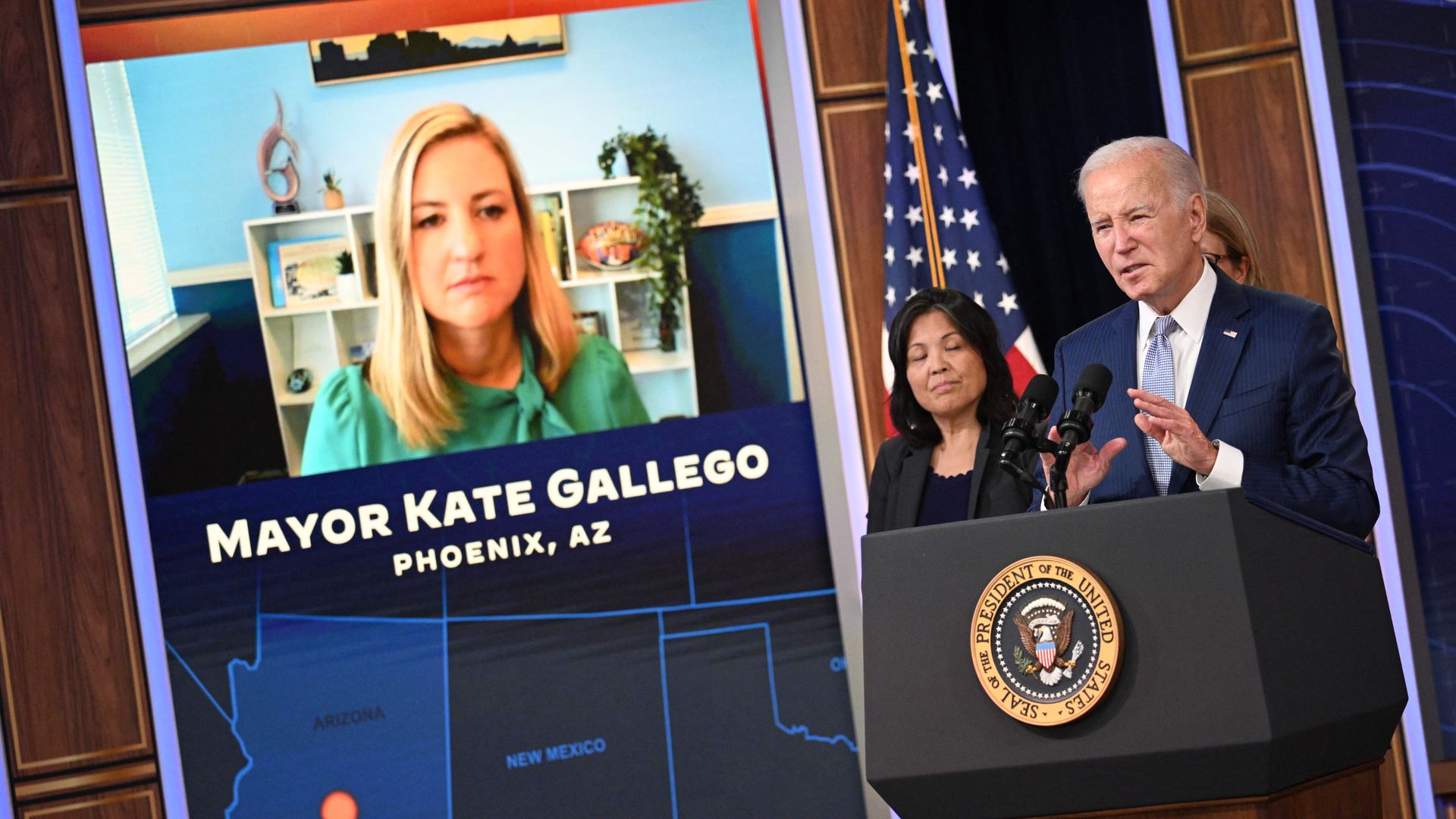 President Biden at a podium with Mayor Kate Gallego on a screen in the background.