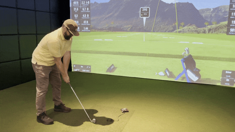 A man makes a golf swing at a simulator. 