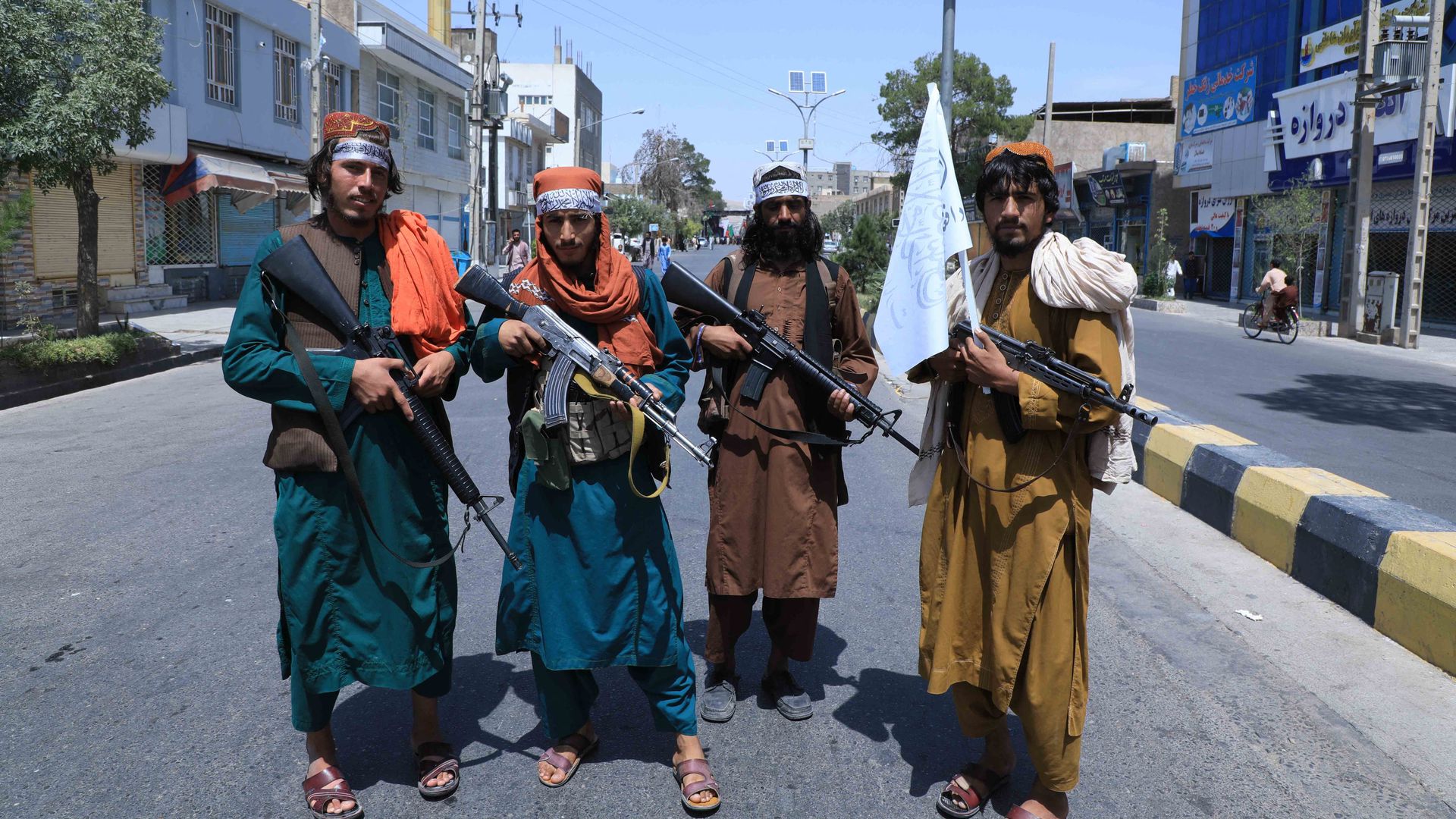 - Taliban fighters stand guard along a road