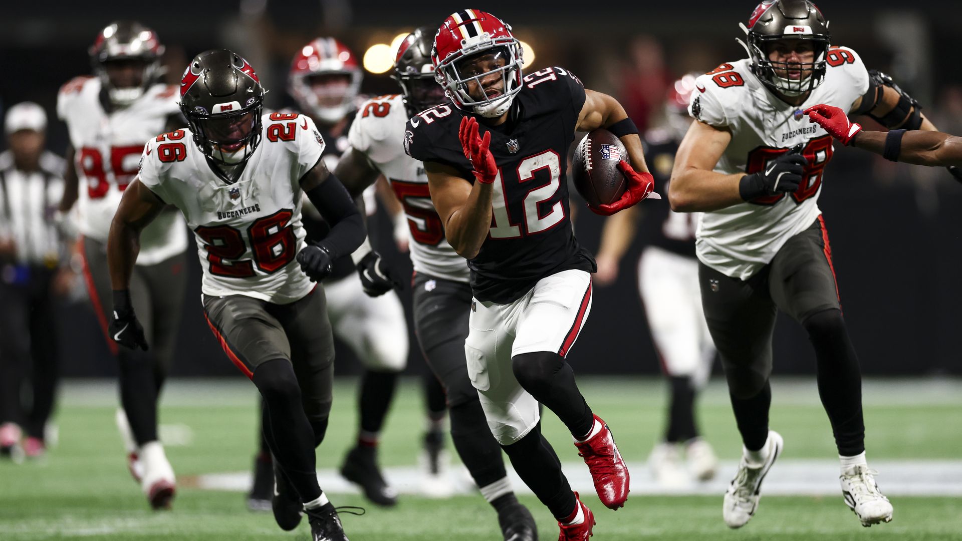 A man in a black uniform runs while carrying a football