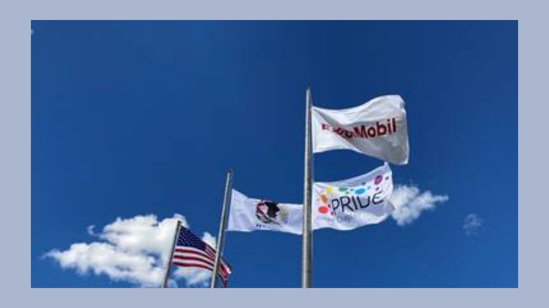 an American flag, an ExxonMobil flag, an ExxonMobil Pride flag against blue sky with white clouds